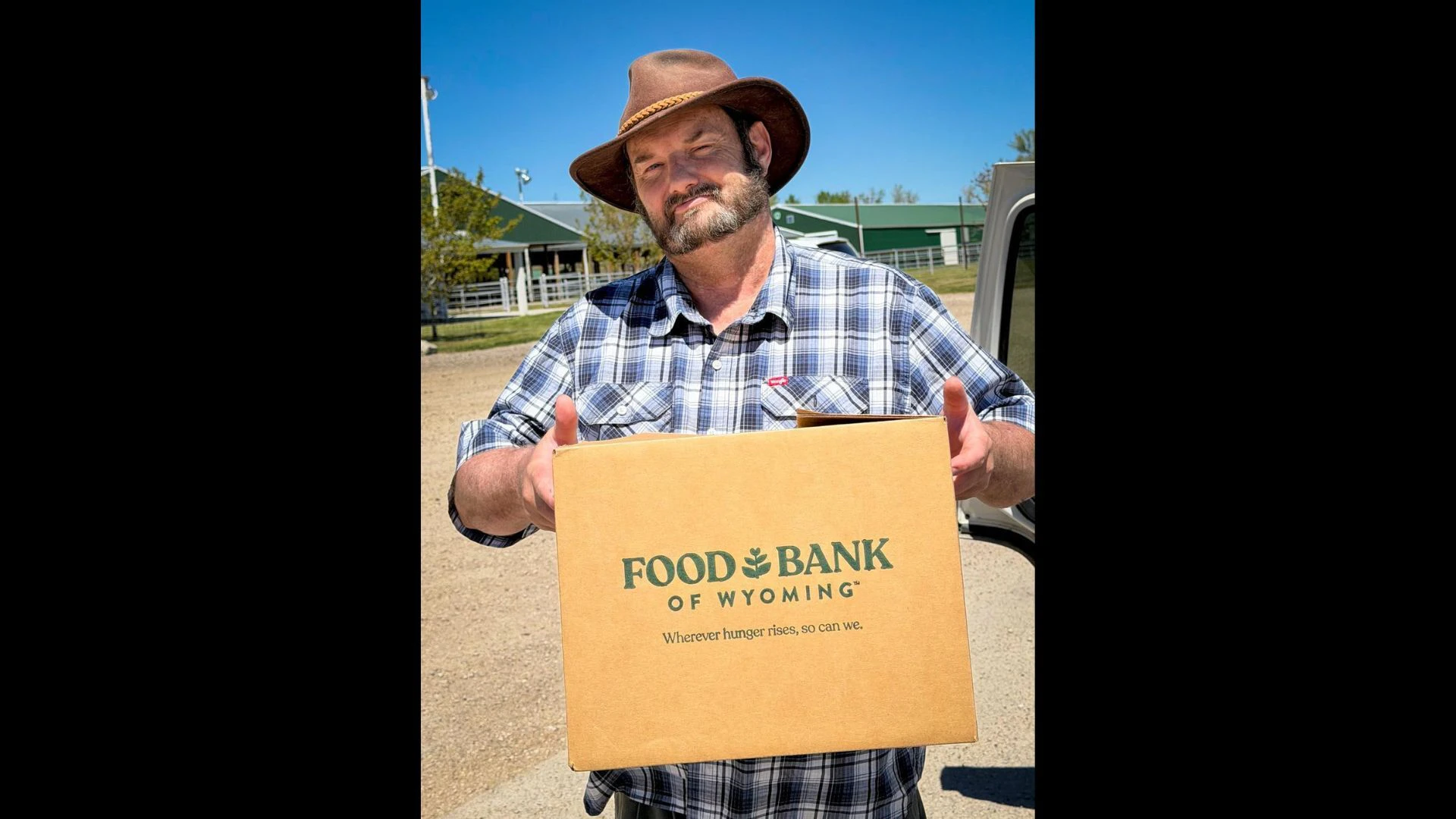 A man wearing a hat, holding a box, volunteering for Food Bank of Wyoming.