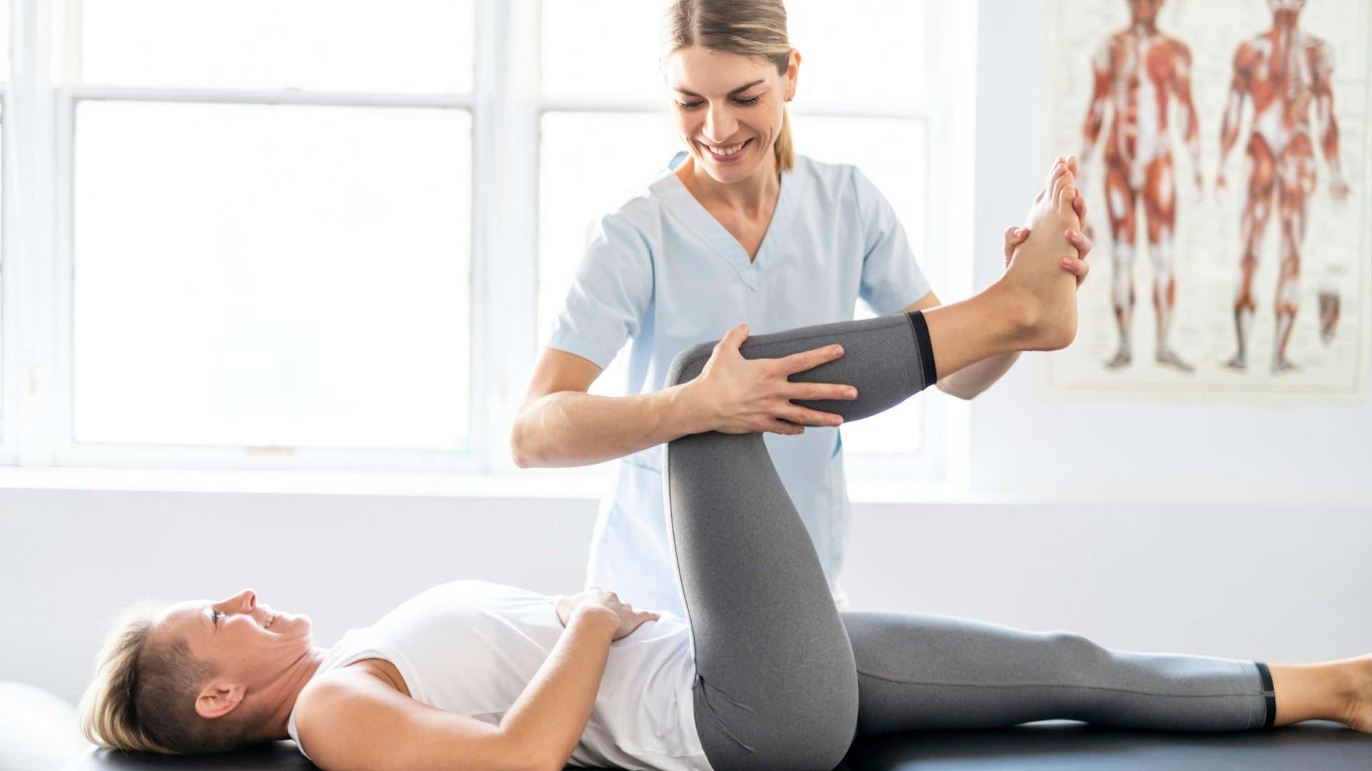 In a physical therapy office, a woman performs a procedure on a patient.