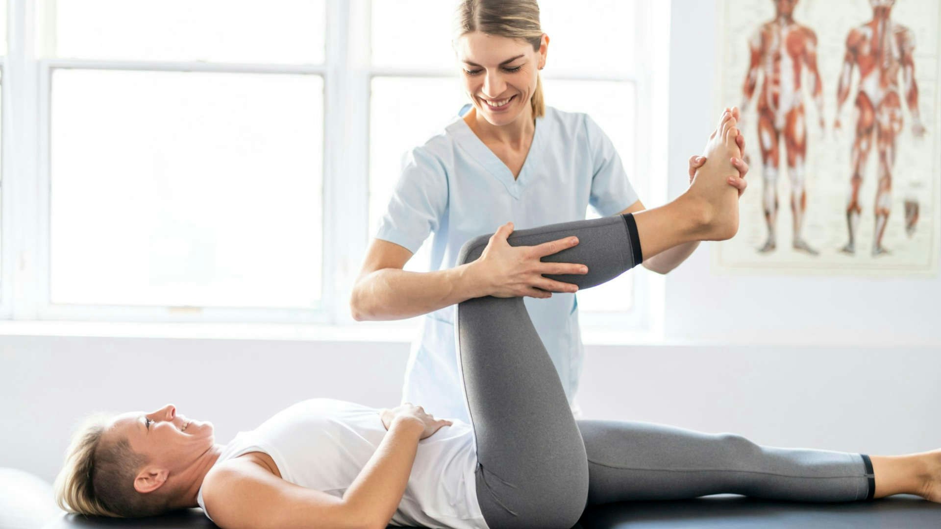 In a physical therapy office, a woman performs a procedure on a patient.
