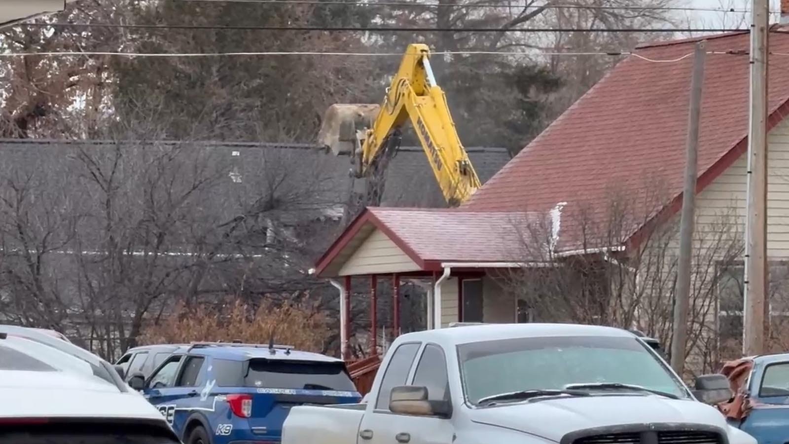 An excavator is used to rip open a house in Sheridan where a suspected cop killer had barricaded himself.