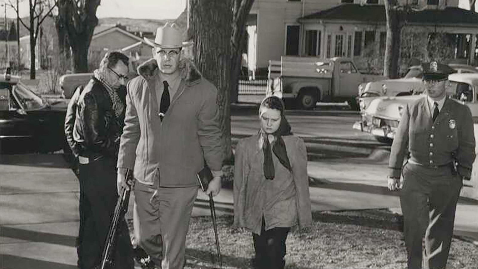 Natrona County Deputy Sheriff Bill Romer escorts Caril Fugate into the Converse County Sheriff’s Office. He carries weapons confiscated from Charles Starkweather.