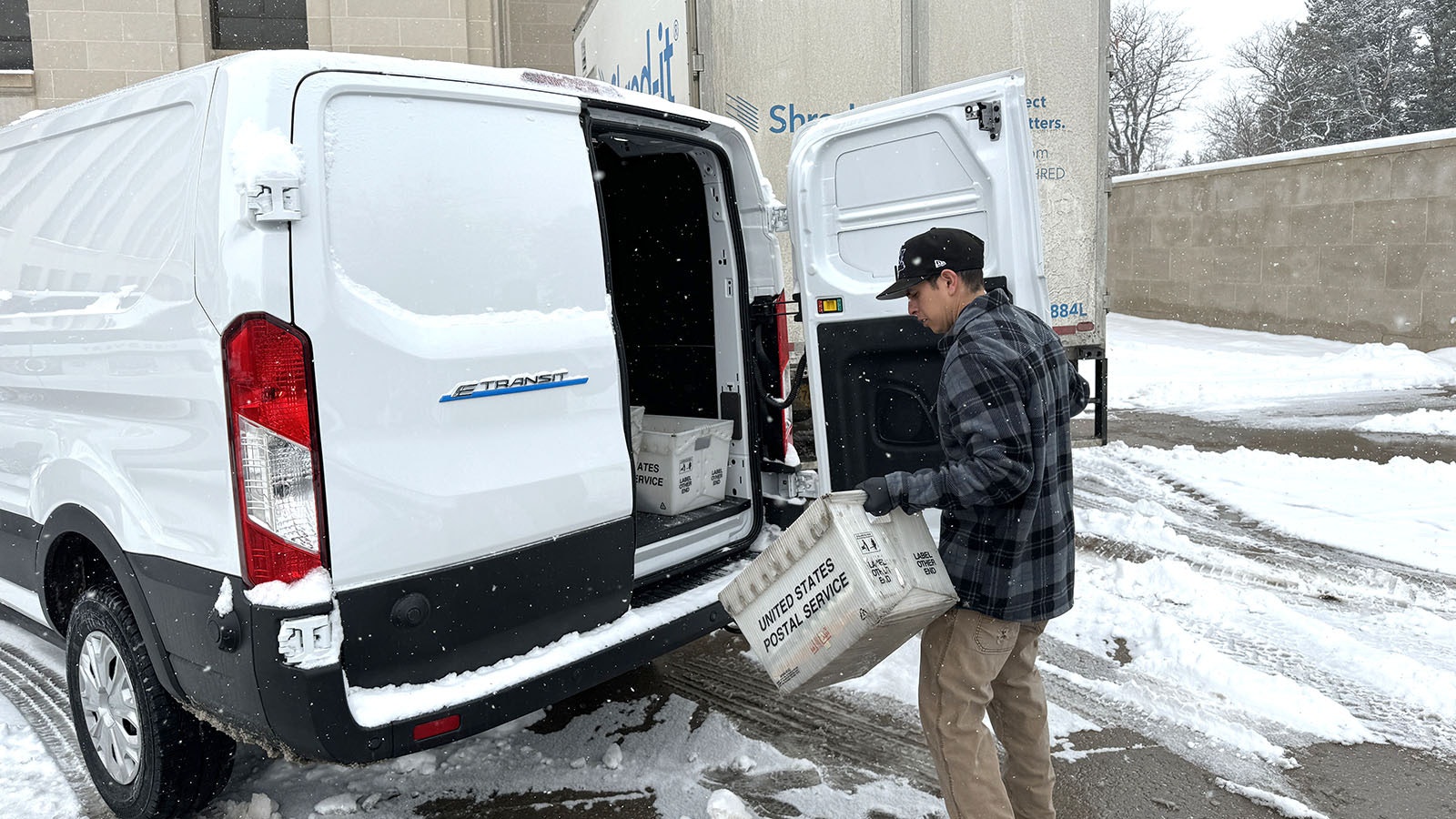 Danny Barela opens the rear door of one of two electric-powered cargo vans owned by Wyoming in front of the state’s Department of Agriculture.
