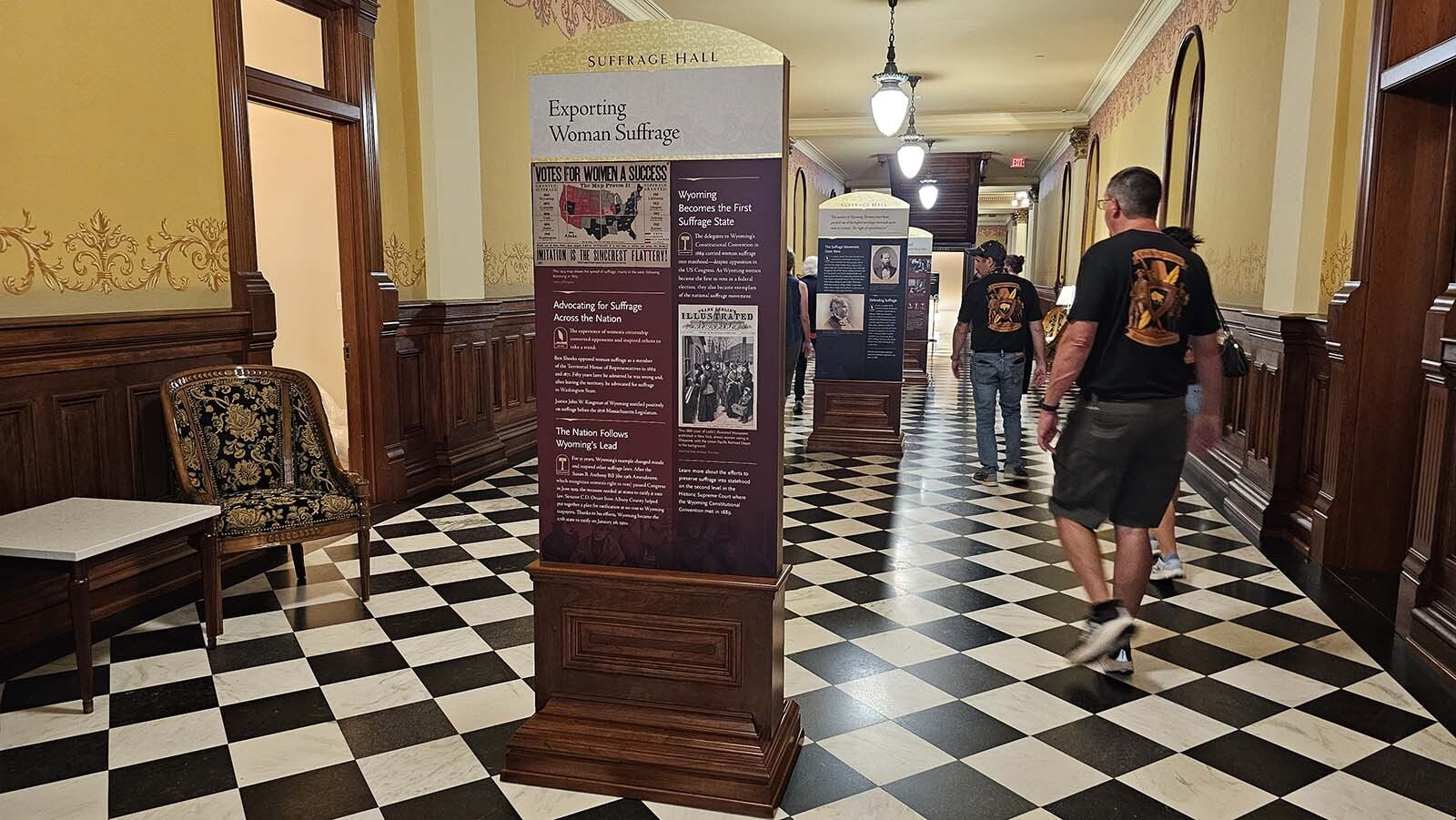 People walk down Suffragette Hall, a newly established exhibit at the Capitol of Wyoming, which tells the history of the Equality State.