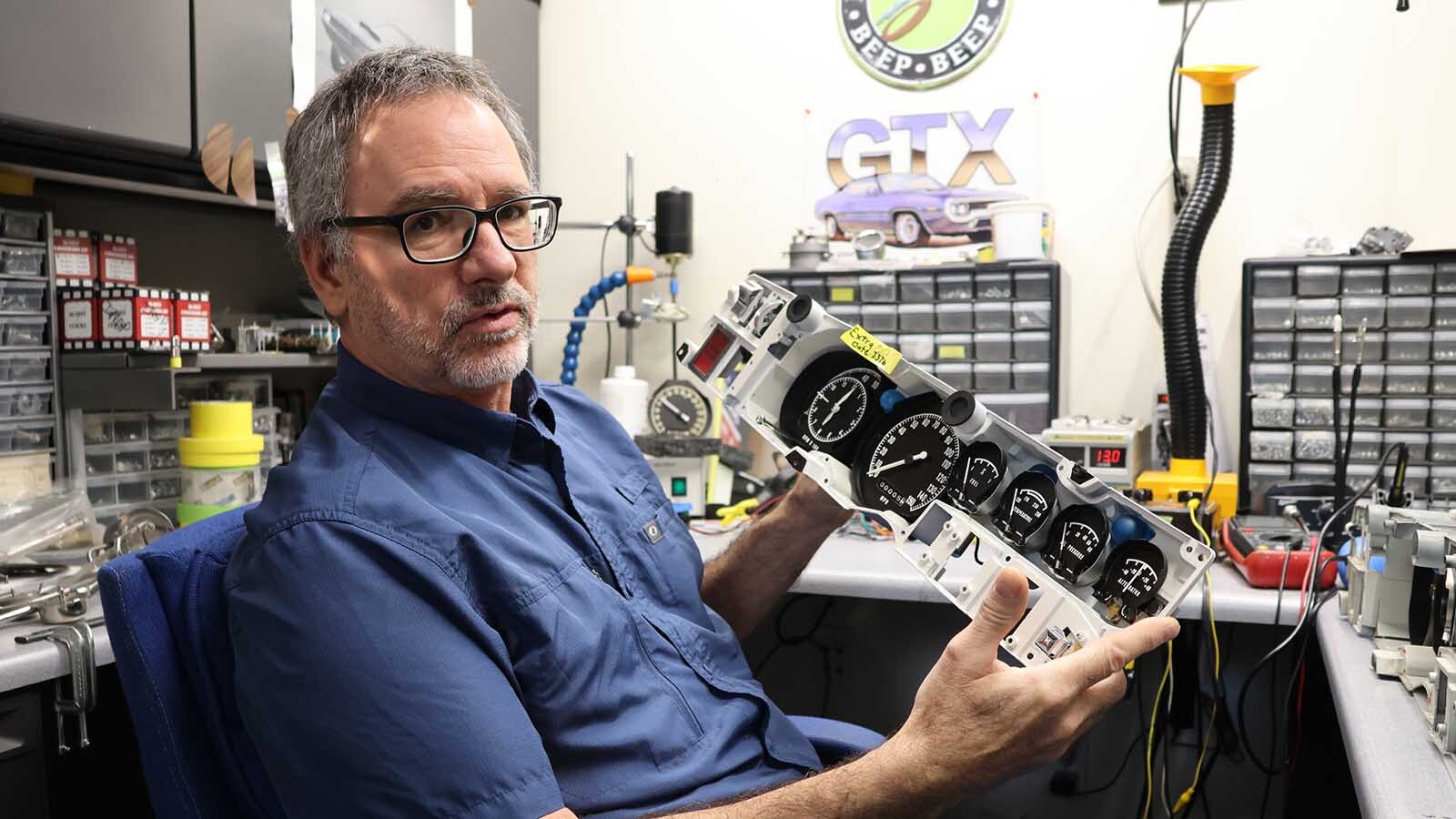Steve Cutler holds a Mopar gauge panel that he has restored.