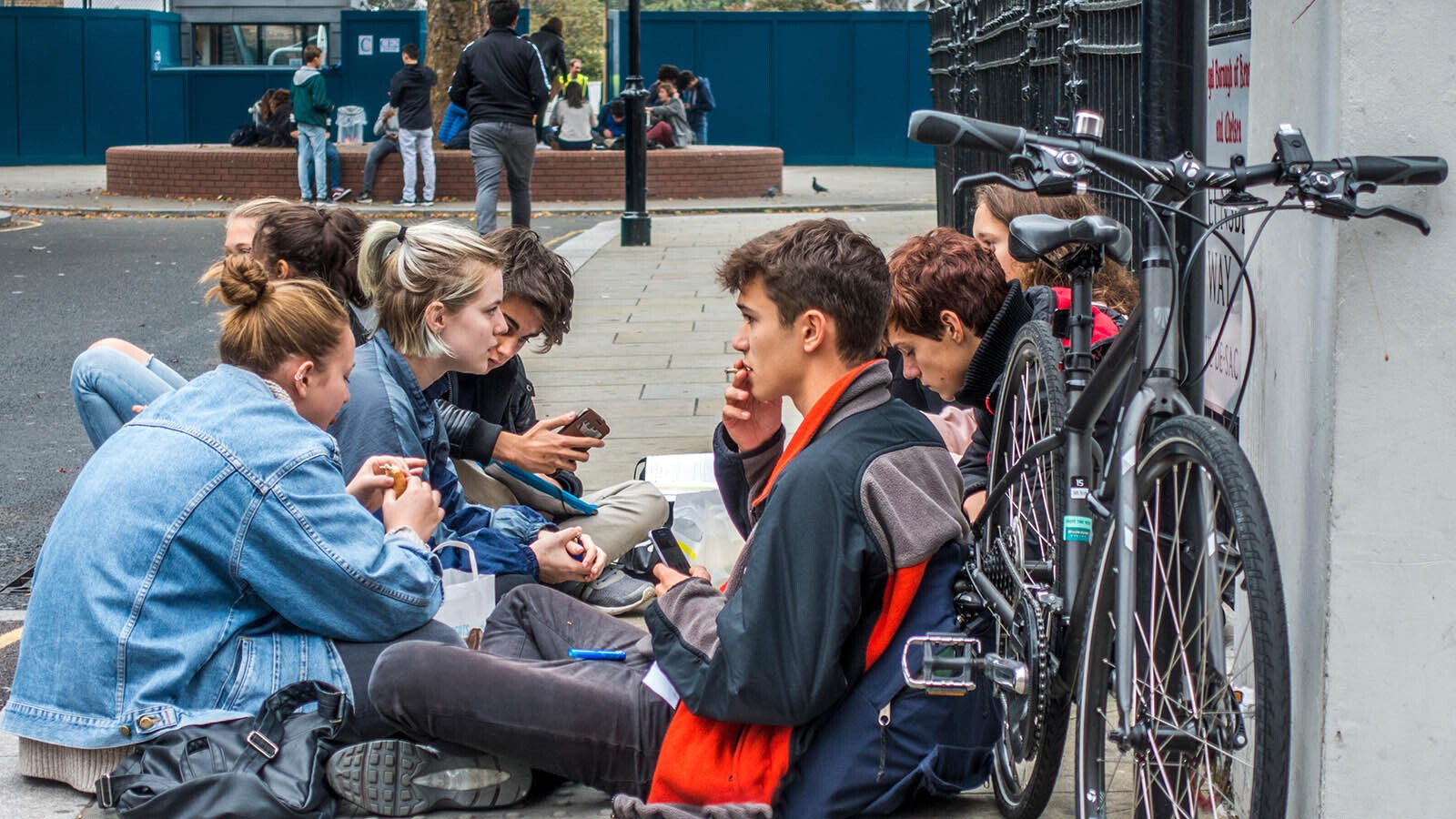 A group of students smoke and talk outside a public school.