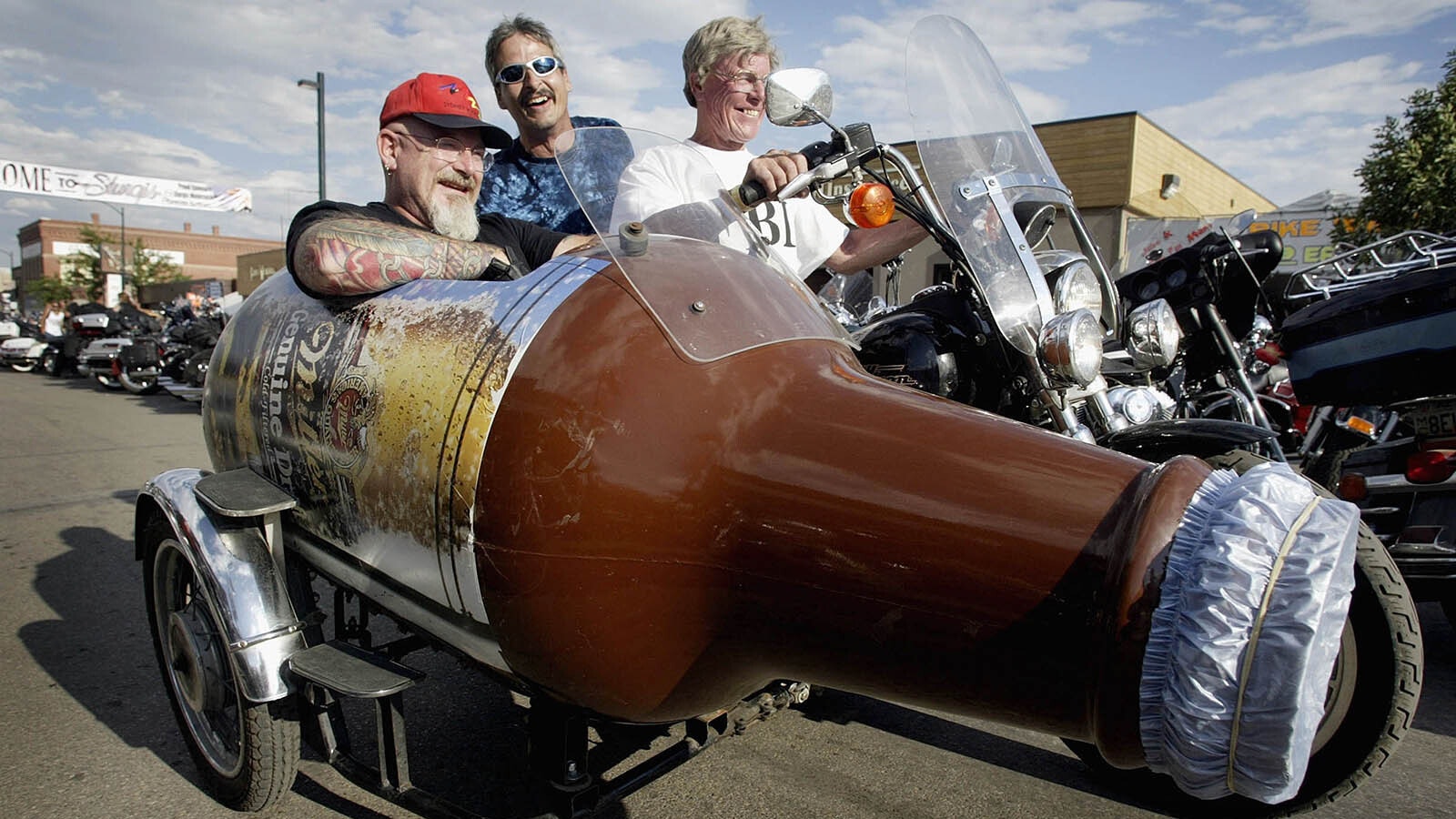 A biker rides his motorcycle with a sidecar shaped like a beer bottle through downtown Sturgis.