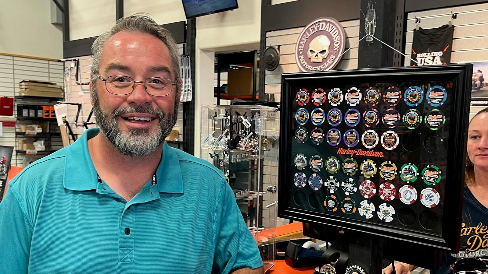 Deluxe Harley-Davidson Business Manager Bryce Cowen stands next to various versions of poker chips featuring the store.