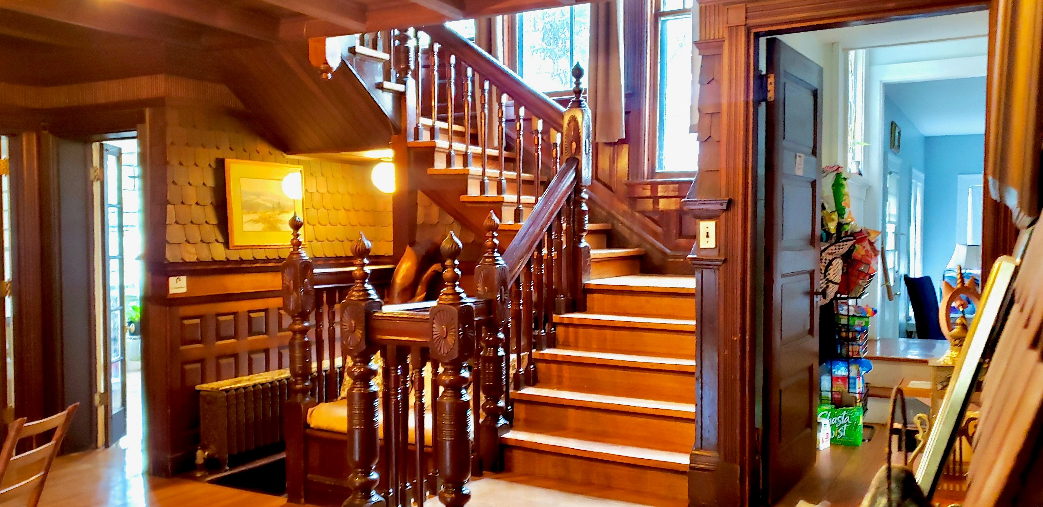 The staircase in the living room is a grand feature of the home that includes a built-in bench and is made of solid, intricately carved wood.