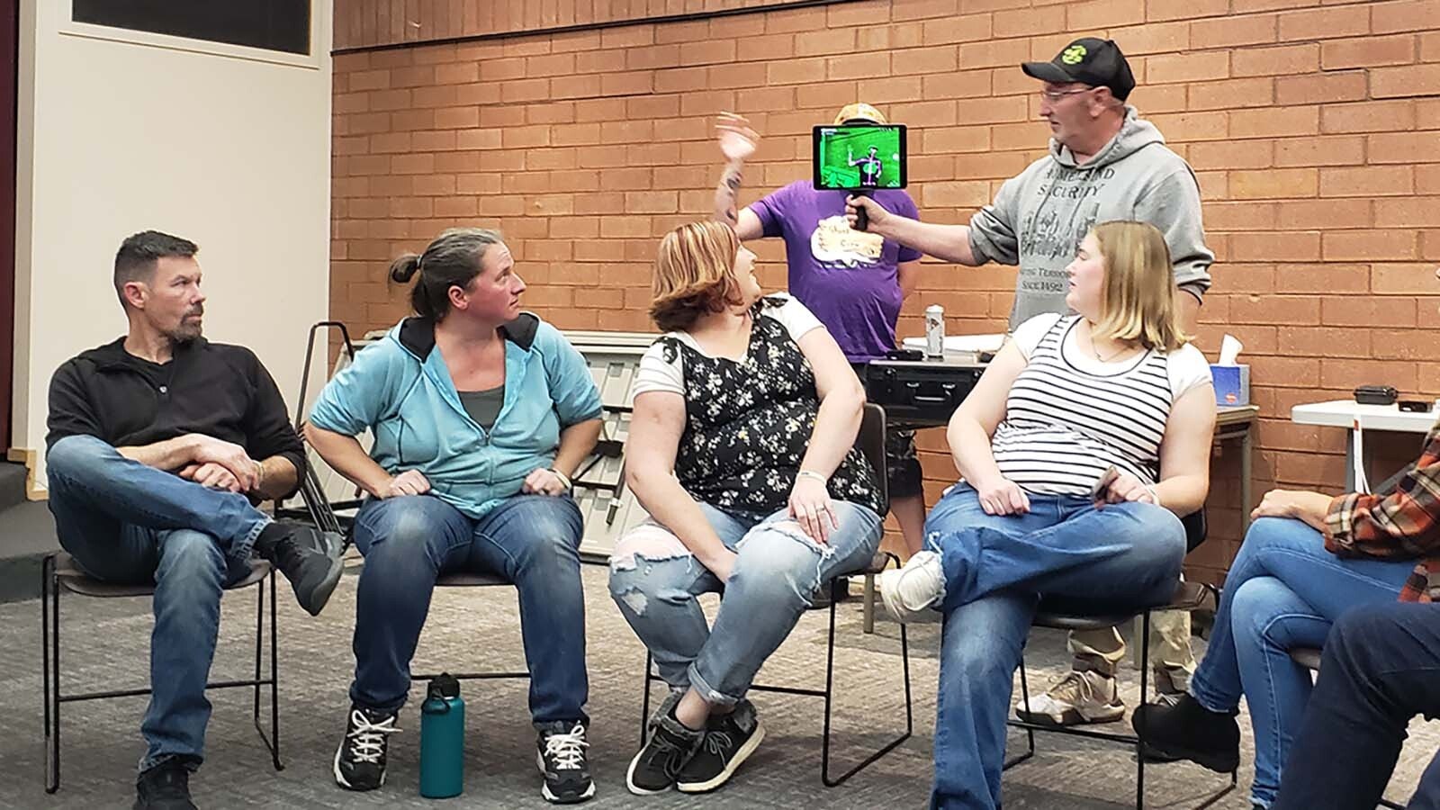 A member of a local paranormal investigations group holds up a device for spotting disturbances in electromagnetic energy to explain how to use it to people taking one of the Sweetwater County Library's Ghost Tours.