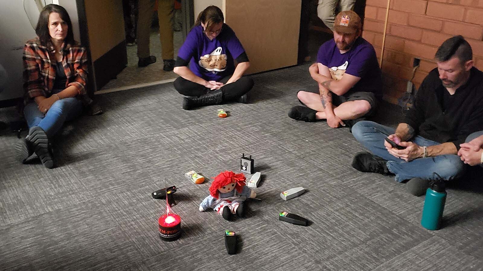 People sit in a circle around a group of K-II devices in a circle around a doll that the library's ghost children are said to like. The ghosts are politely asked to light up all of the devices at once. The devices monitor electromagnetic energy. Paranormal investigators believe spirits can interact with EMF signals.