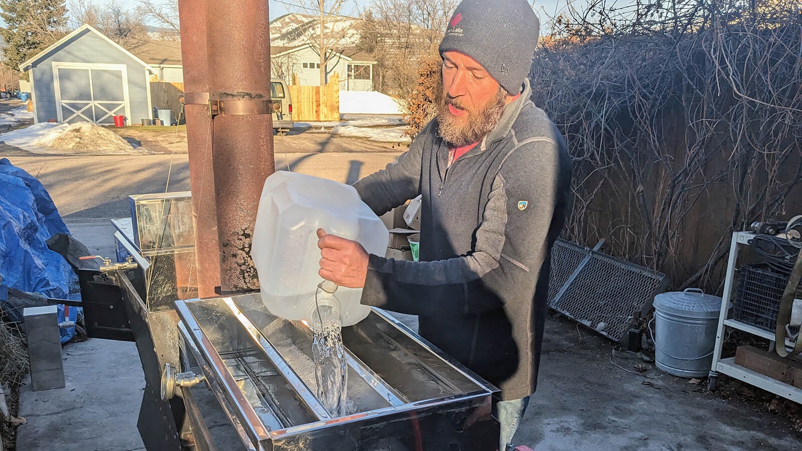 David Knudson pours the sap from a silver maple tree in one of two evaporators in his driveway.