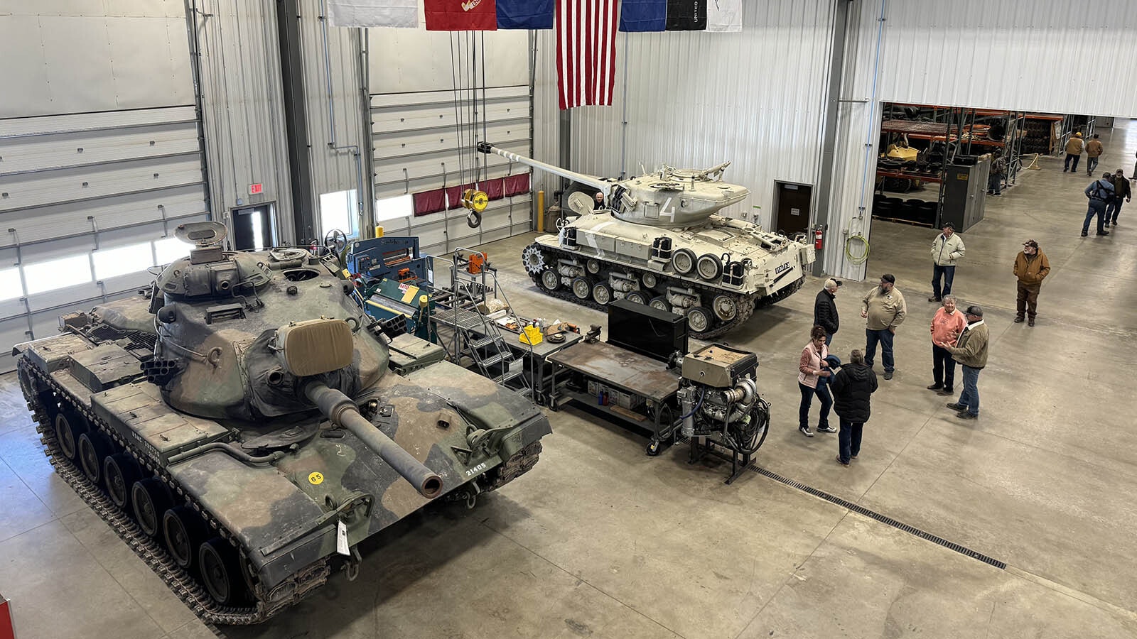 An overhead view of the maintenance bay in the shop. The yellow crane near the ceiling has a 20-ton capacity for moving the enormously heavy components of tanks, trucks, and other military vehicles.