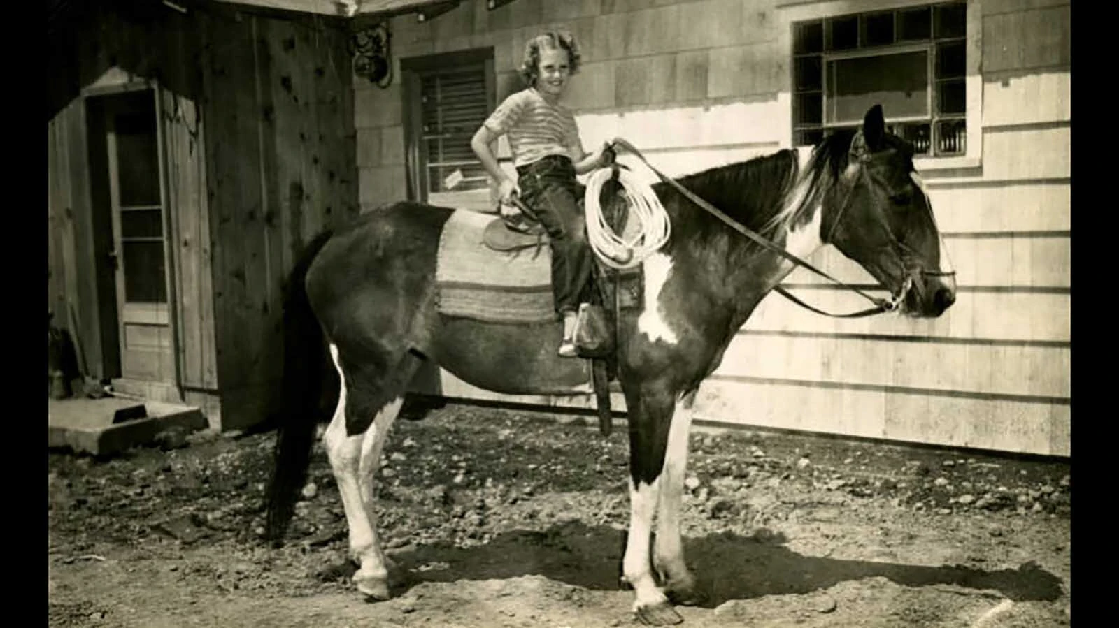 A girl poses on a paint horse sometime between 1910 and 1925.