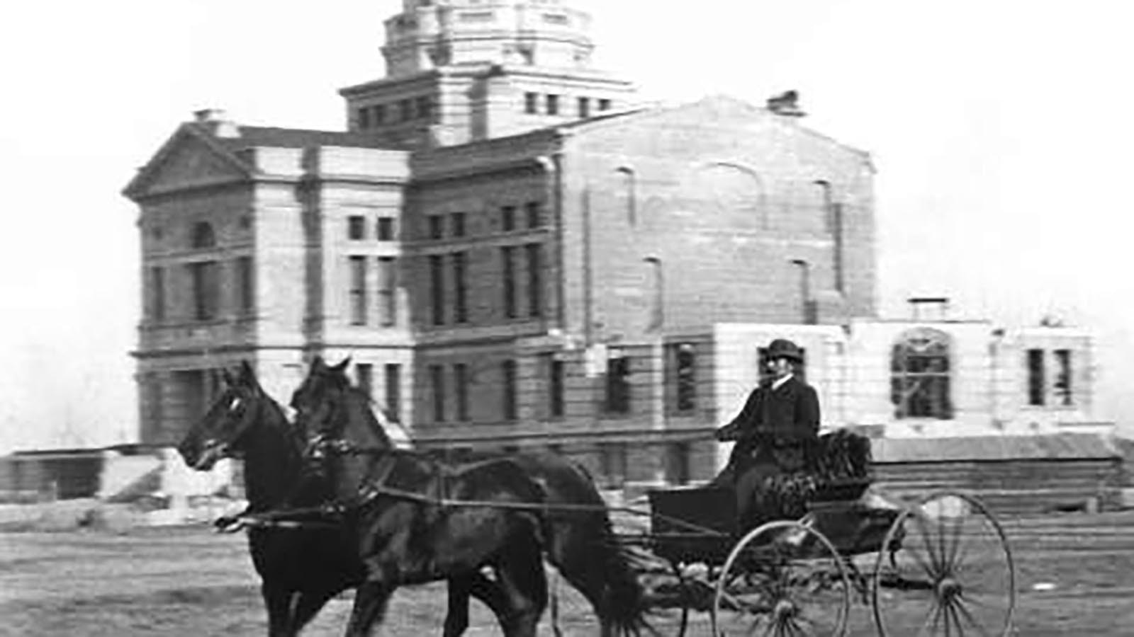 The Wyoming Territorial Capital under construction in 1888. Architect David W. Gibbs is driving past it. The building was finished in 1890, the year Wyoming became a state.