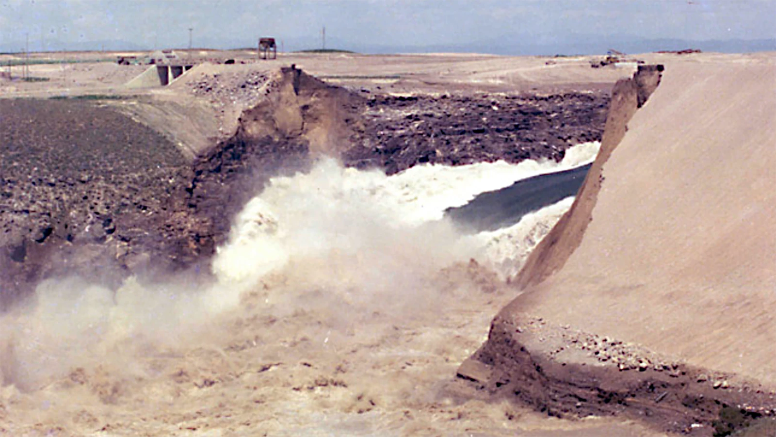 Photos taken at the time of the Teton Dam disaster show how water started leaking and then waters surging through the dam site.