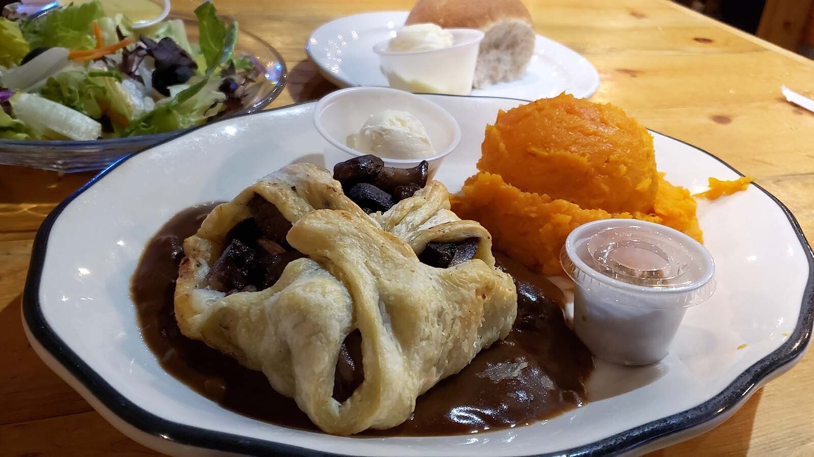 The beef Wellington with a side of sweet potatoes comes with a salad and roll.