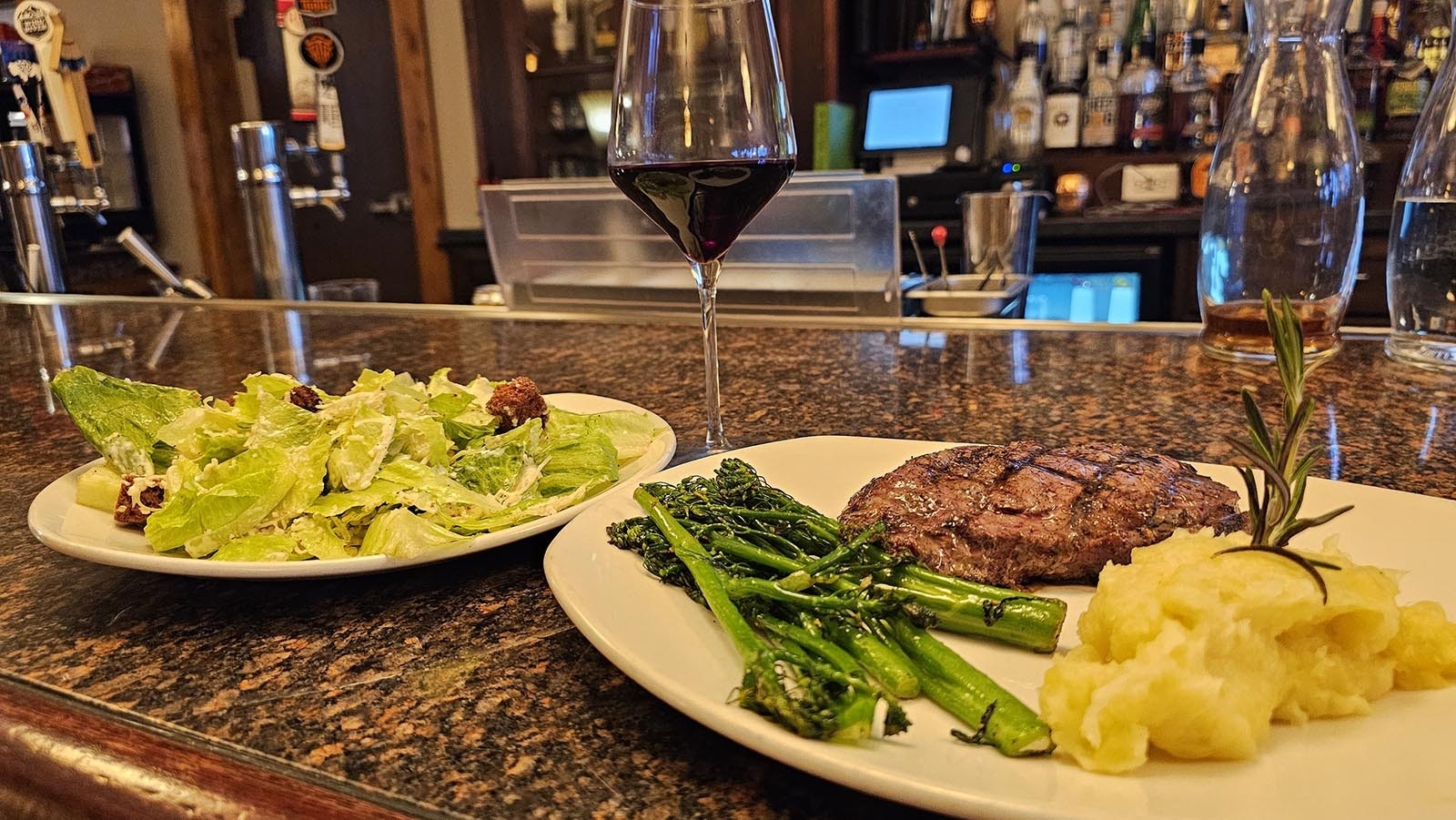 Steak with mashed potatoes and broccolini with a fresh salad and red wine at The Divide Restaurant & Lounge in Encampment.