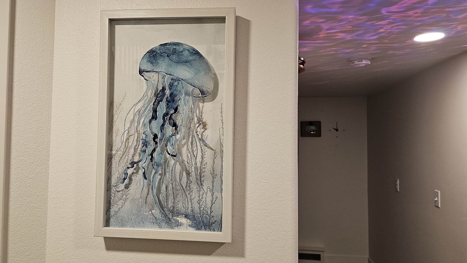 A jellyfish floats on the wall, with ocean wavelets on the ceiling behind.