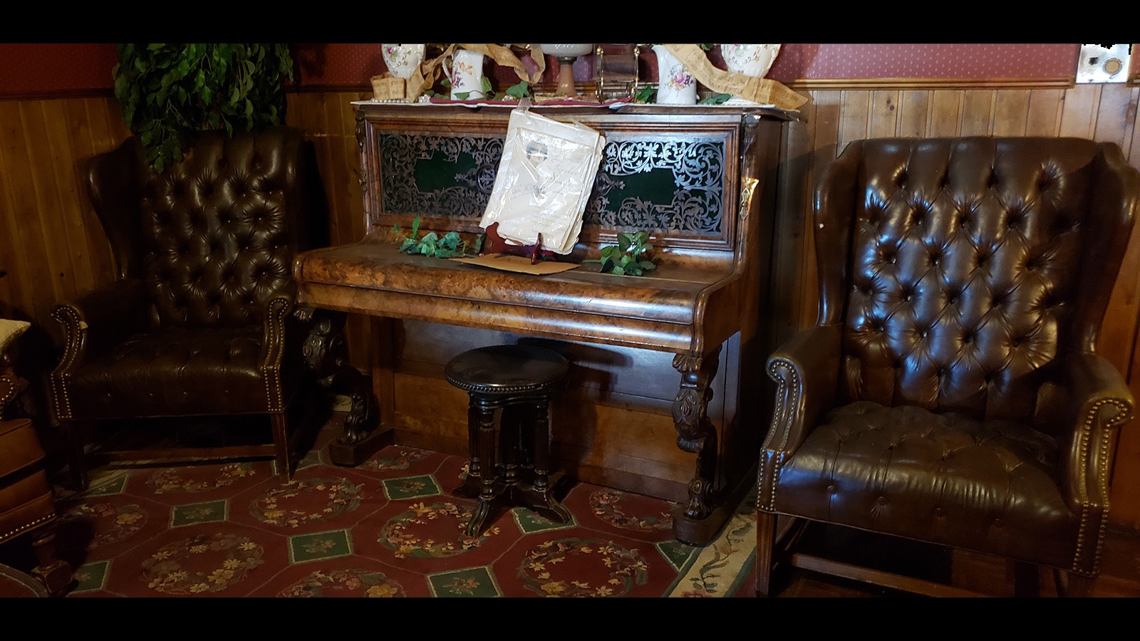 A vintage piano flanked by luxurious antique leather chairs.