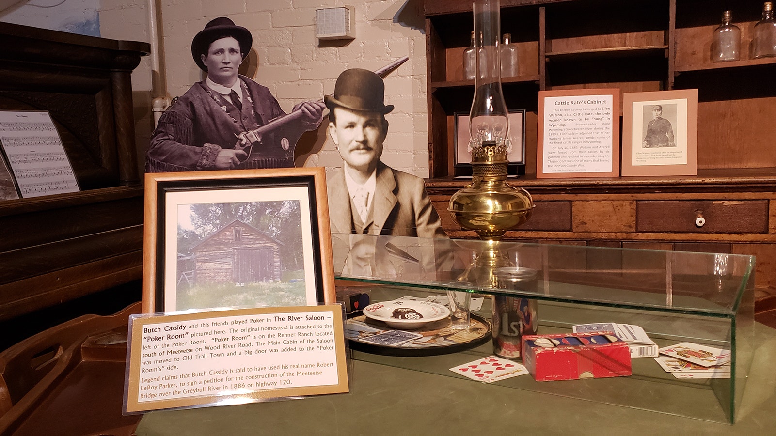 Butch Cassidy and his friends played poker in the River Saloon's Poker Room in Thermopolis, Wyoming. The display recreates what the inside of the pictured cabin might have looked like, but also includes "Cattle Kate's" cabinet.