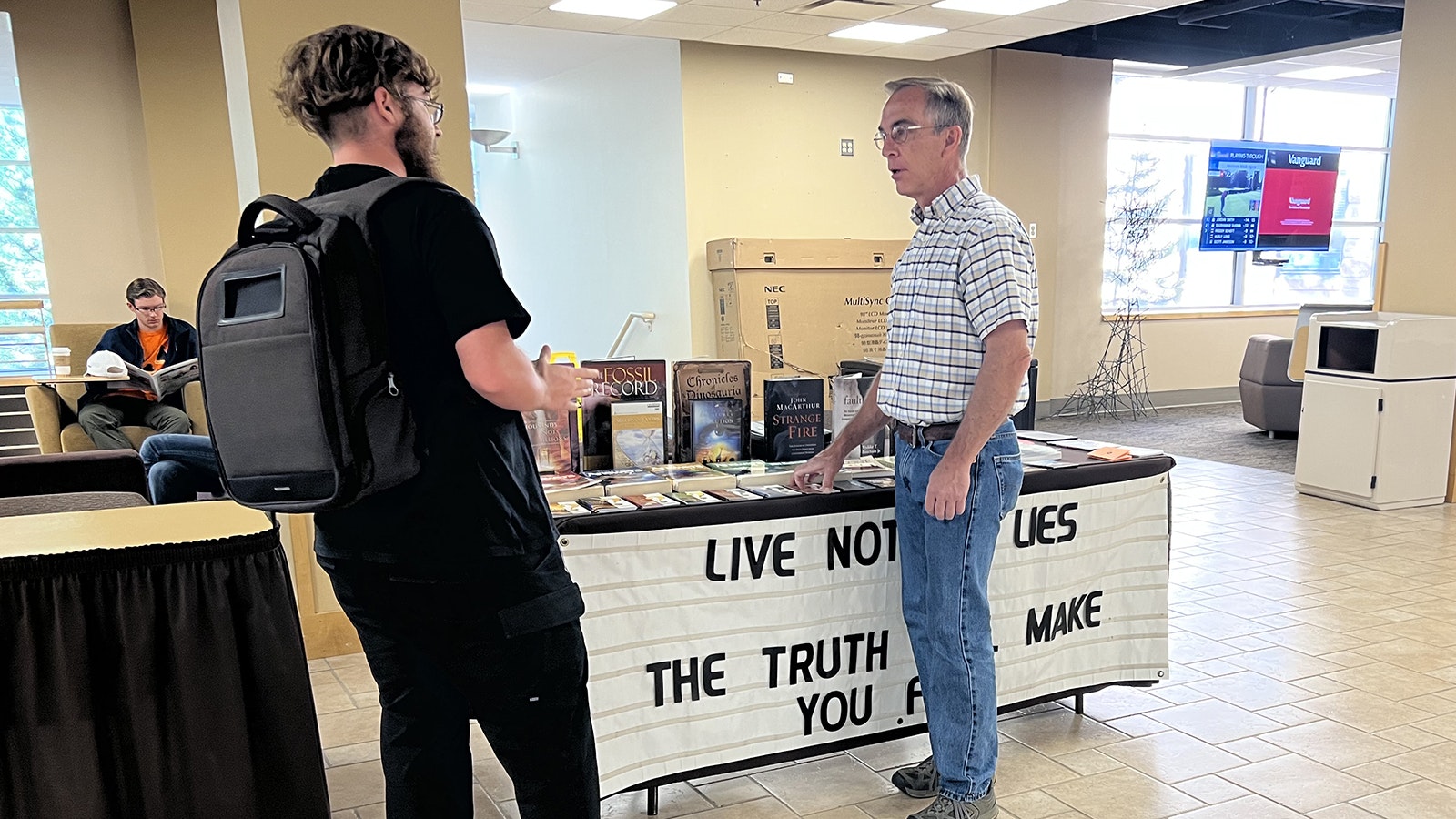 Laramie church elder Todd Schmidt debates religious themes and ideas with a University of Wyoming student recently in the Wyoming Union. Schmidt had been banned from having his table there for a year, but a recent court ruling lifted the ban and he's returned, setting his table up every Friday from 9 a.m. to 5 p.m.