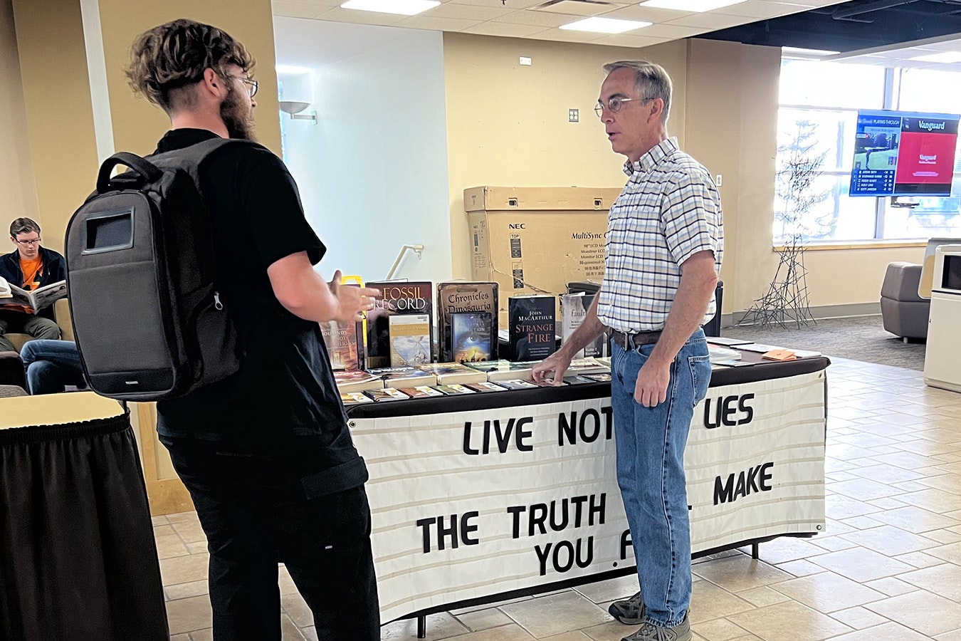 Laramie church elder Todd Schmidt debates religious themes and ideas with a University of Wyoming student recently in the Wyoming Union. Schmidt had been banned from having his table there for a year, but a recent court ruling lifted the ban and he's returned, setting his table up every Friday from 9 a.m. to 5 p.m.