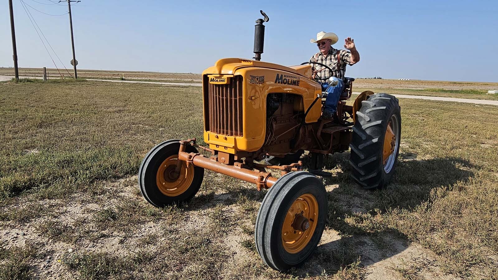 Dale Hiatt waves at Cowboy State daily on his Minneapolis Moline tractor during the  Centennial Antique Tractor and Engine Club's annual tractor drive.