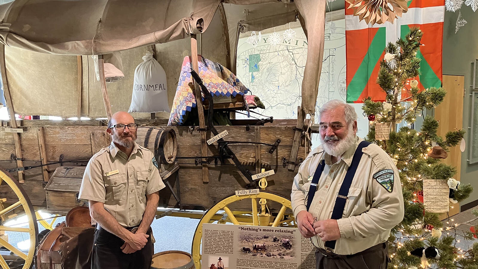 Historic Interpretive Center specialists Jason Vlcan, left, and Reid Miller pose with a re-enactor’s wagon that actually traveled the Oregon Trail twice.