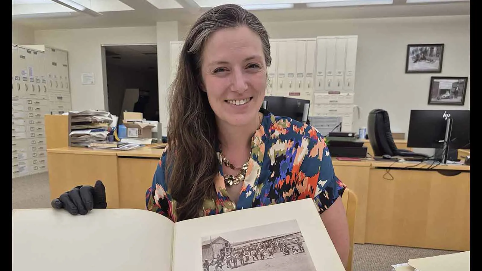 Suzi Taylor, reference archivist at the Wyoming State Archives in Cheyenne, examines a photograph of cowboys that Charles Kirkland took at the Diamond Ranch near Chugwater.