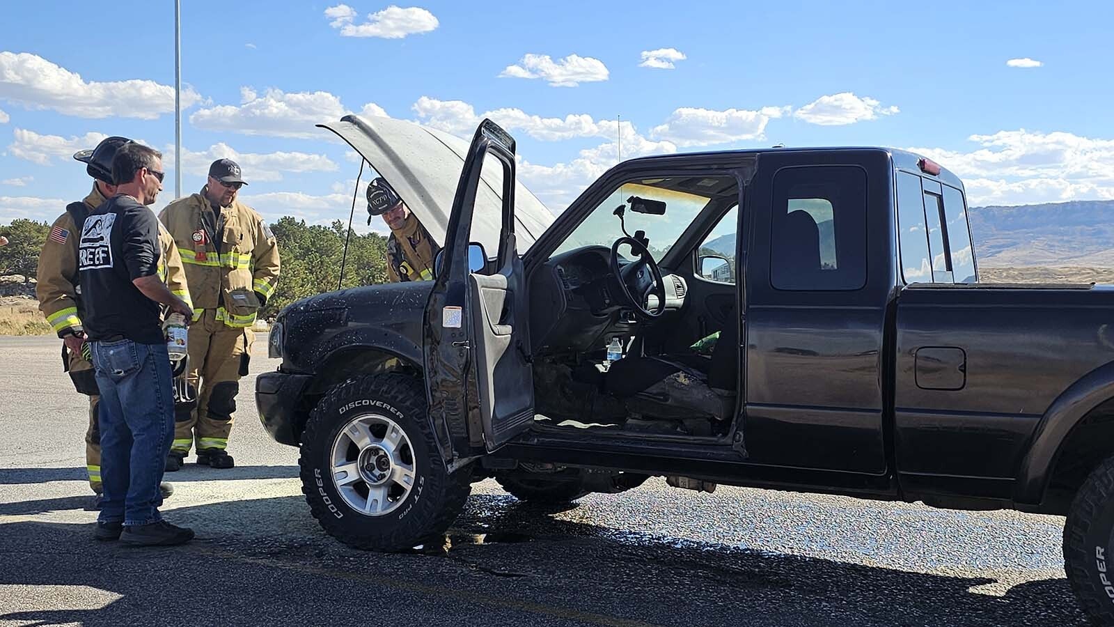 Firefighters gather around Nathan Frederick's truck at the Hat Six exit near Casper. A fire unexpectedly started under the hood after Frederick's truck was struck by something from a passing semi.