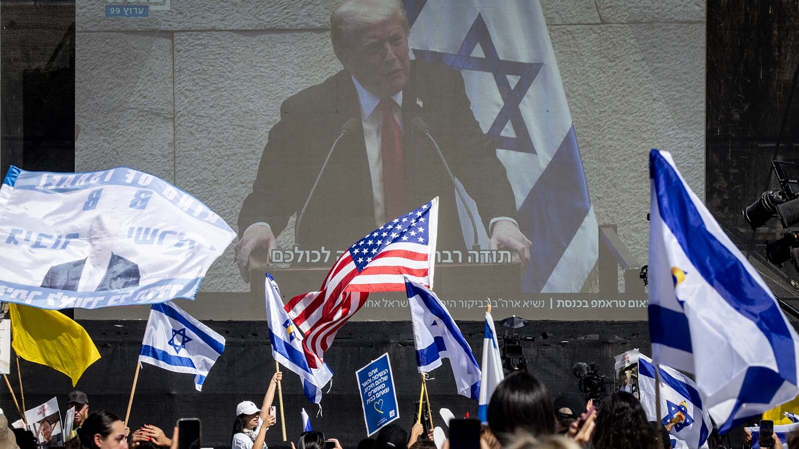 People watch U.S. President Donald Trump address the Knesset, Israel's parliament, on a giant screen in Hostages Square on Oct. 13, 2025 in Tel Aviv, Israel. The ceasefire deal between Israel and Hamas has brought an end to the two years of war that followed the attacks of Oct. 7, 2023. A condition of the deal was the immediate return of 48 hostages held in Gaza, around 20 of whom were believed to be alive.
