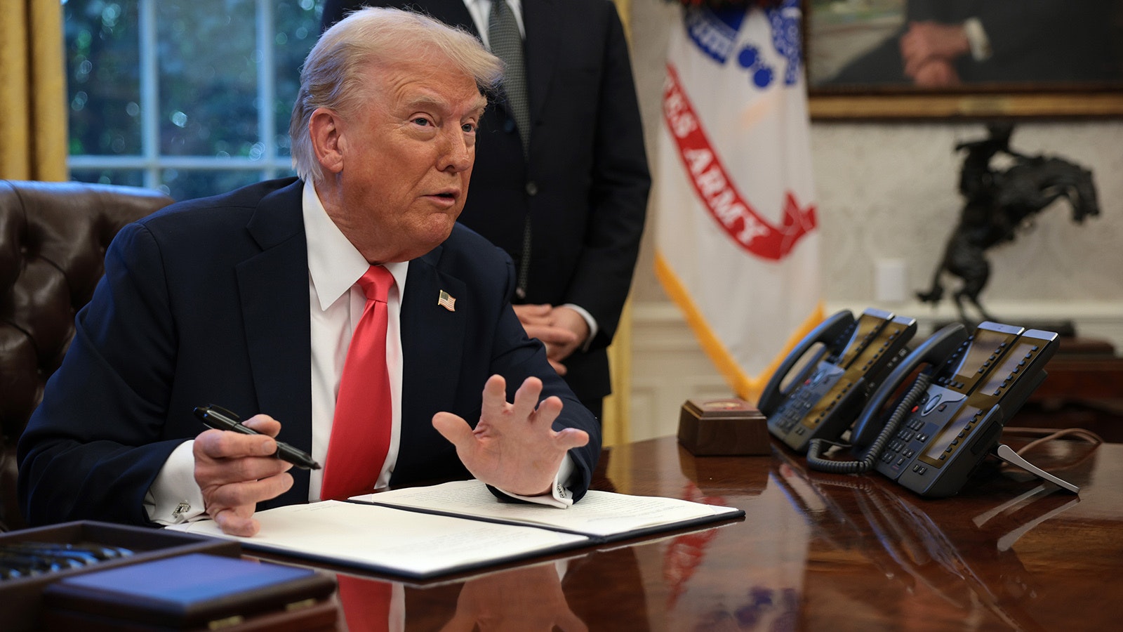 President Donald Trump signs an executive order in the Oval Office.