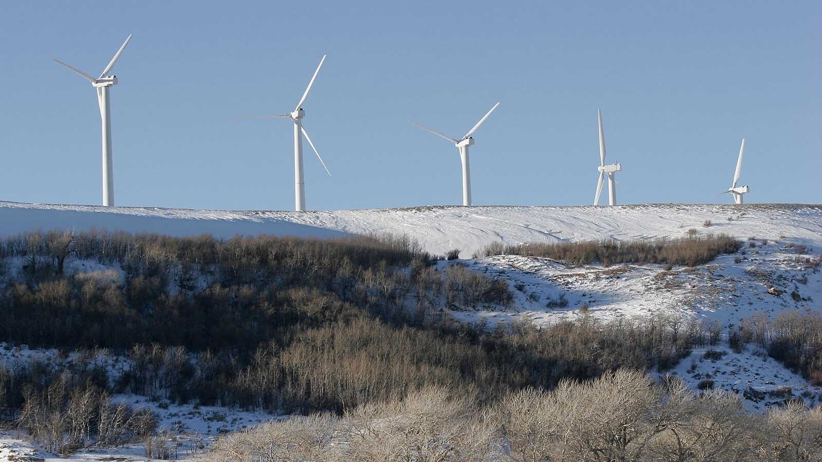 Wind turbines over a snowy hill in southern Wyoming.