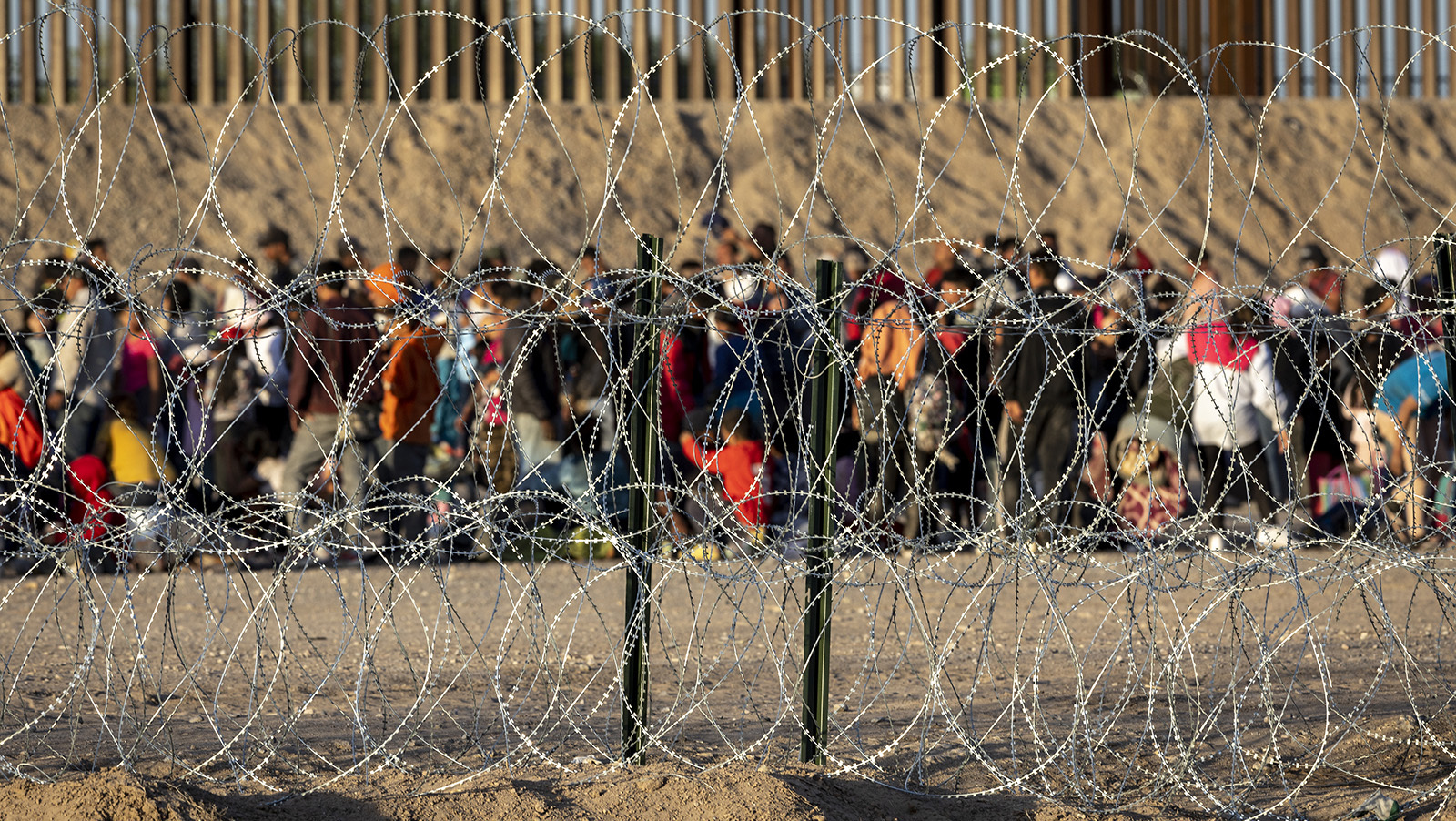 Immigrants wait near the U.S.-Mexico border fence after crossing over from Mexico on Tuesday in El Paso, Texas. A surge of immigrants is expected with the end of the U.S. government's Covid-era Title 42 policy, which for the past three years has allowed for the quick expulsion of irregular migrants entering the country.