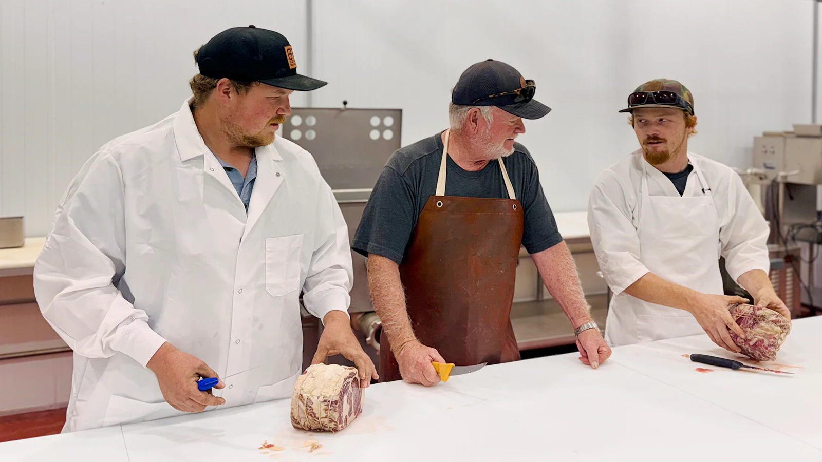 Broderick Thomas, the Becks' son, prepares a cut of meat alongside his father, Dana, and ranch hand Quinton Boyles.