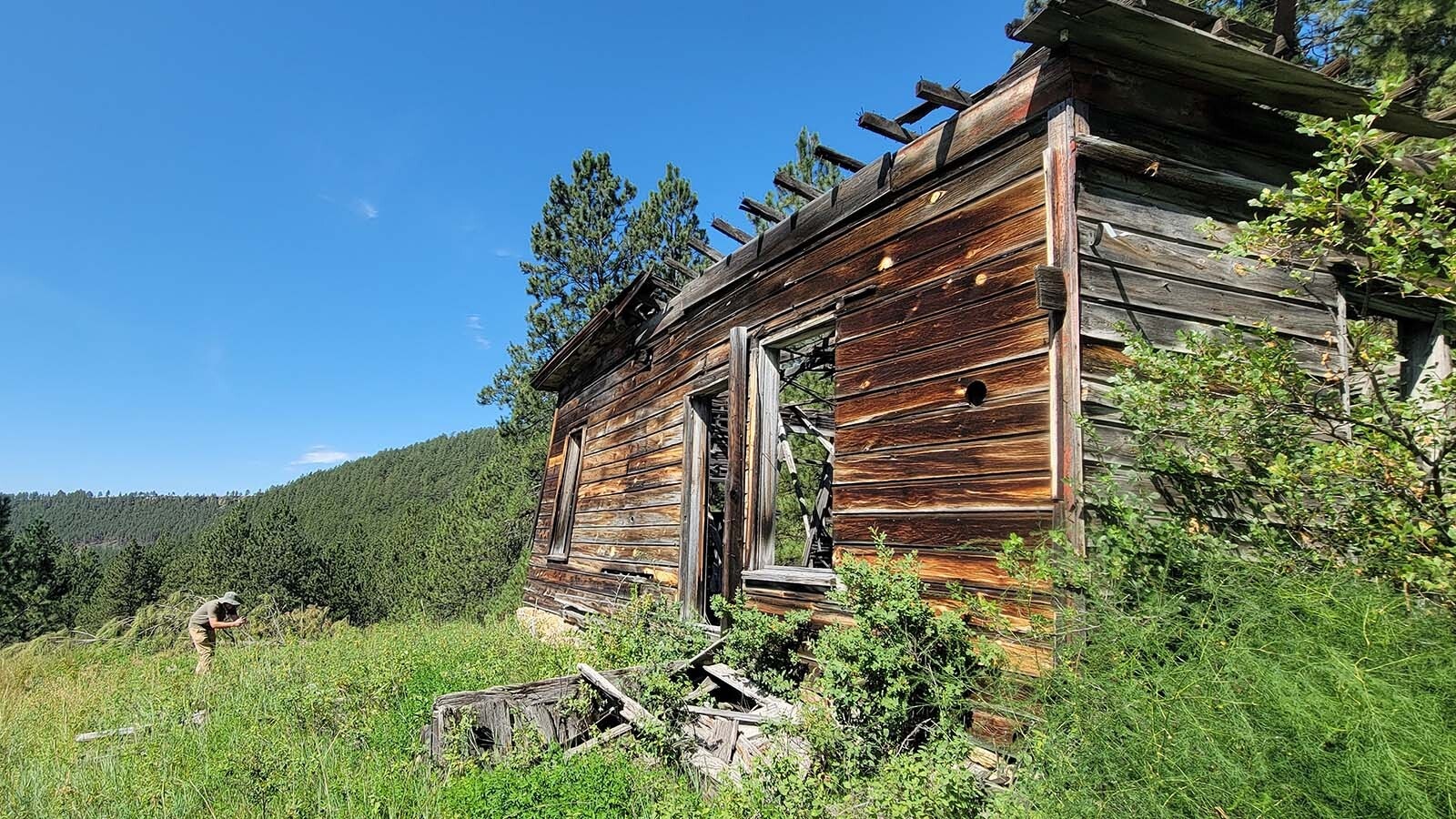 One of the crew members of History Under The Pines photographs an old home in a once vibrant company town now which is now an abandoned ghost town in Wyoming.