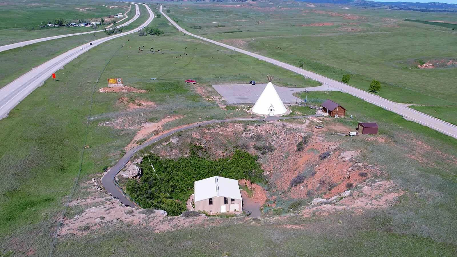 A ancient 200-foot-wide sinkhole with up to 20,000 bones from an Indigenous buffalo jump forced Wyoming to re-route I-90 in 1969. Here, the interstate to the left curves to avoid the site.