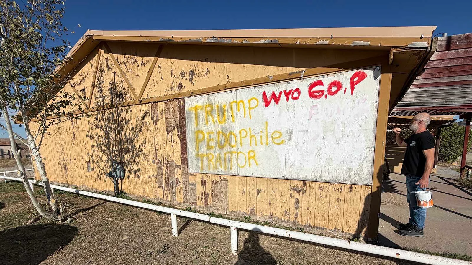 A man who declined to give his name paints over portions of a message saying "KILL THE RICH" on Monday afternoon, saying he is going to change it to "HEAL THE RICH" instead.