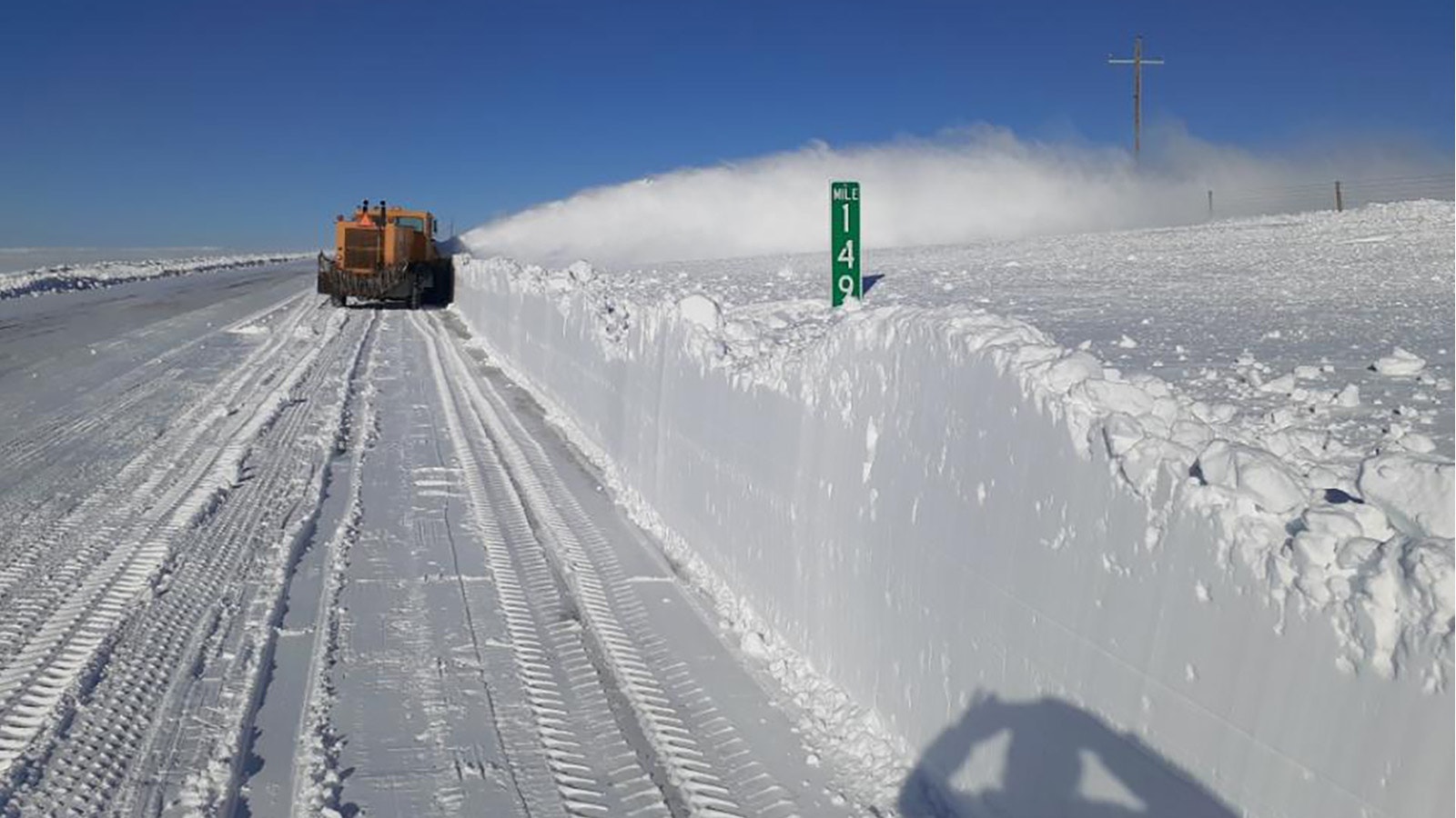 A snowplow clears a large drift from the side of Interstate 80.