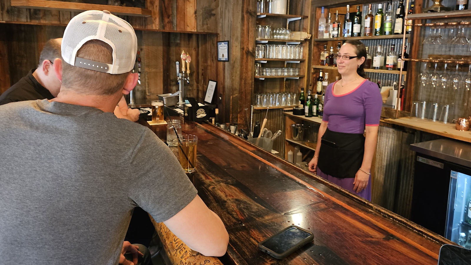 A waitress listens as bar patrons discuss the impending winter closure for the Wagon Box in Story, which took customers and workers by surprise last winter.