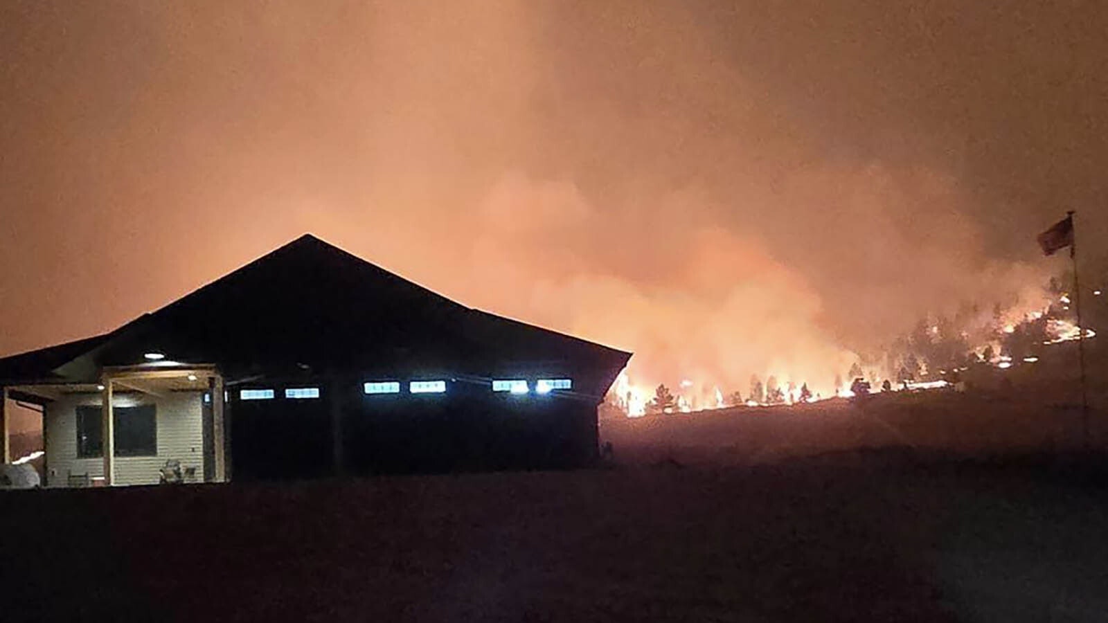 The Elk Fire rages around Warren Titschler's home near Dayton, Wyoming. With a hose and a water tank, he protected it through a frightening night of out-of-control wildfire activity.