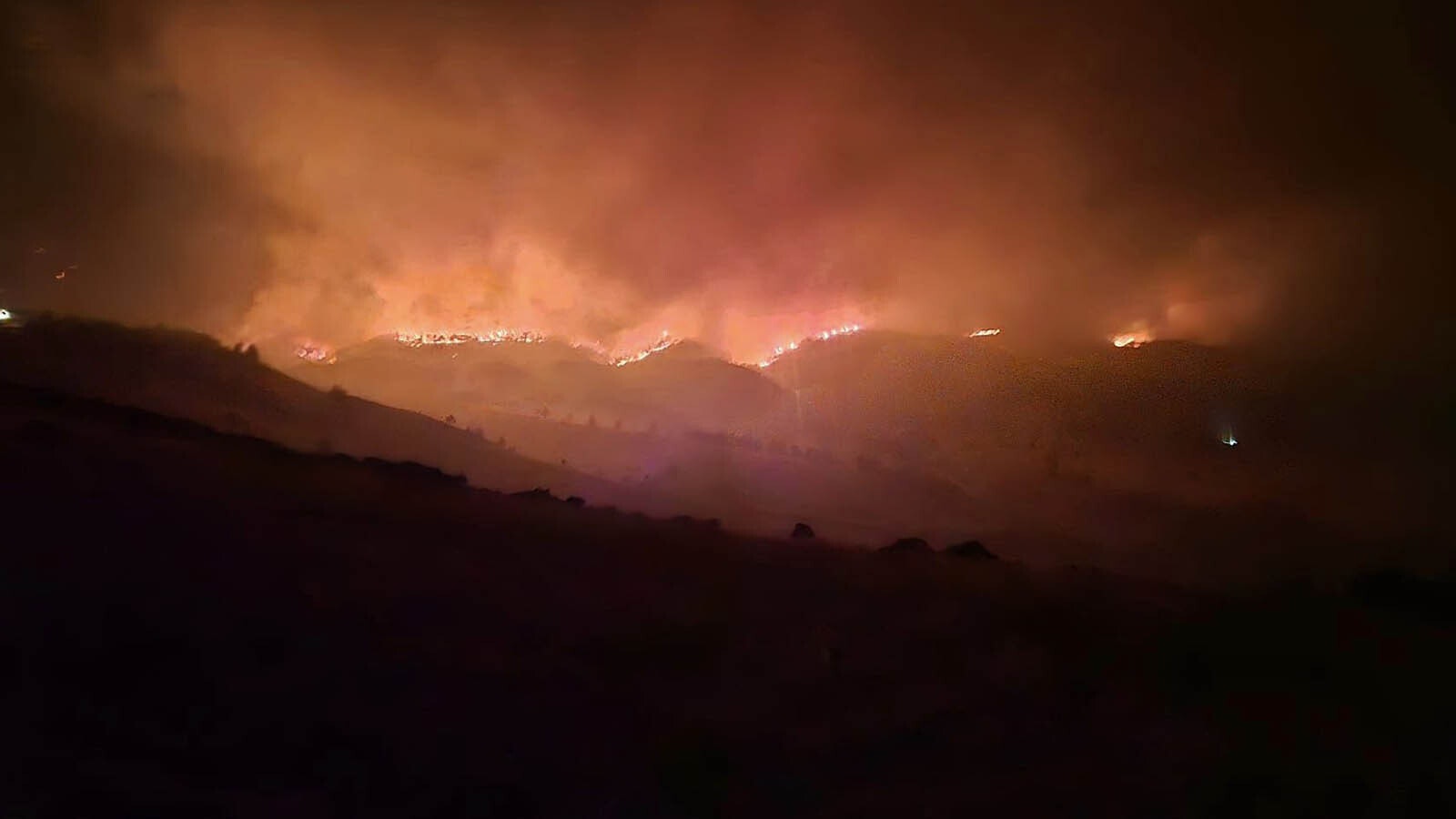 The Elk Fire rages around Warren Titschler's home near Dayton, Wyoming. With a hose and a water tank, he protected it through a frightening night of out-of-control wildfire activity.