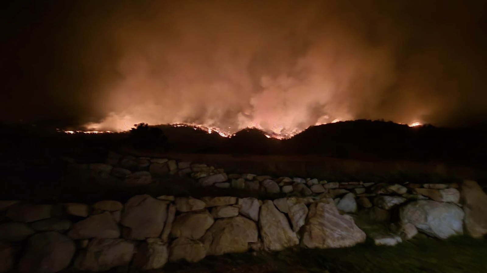 The Elk Fire rages around Warren Titschler's home near Dayton, Wyoming. With a hose and a water tank, he protected it through a frightening night of out-of-control wildfire activity.