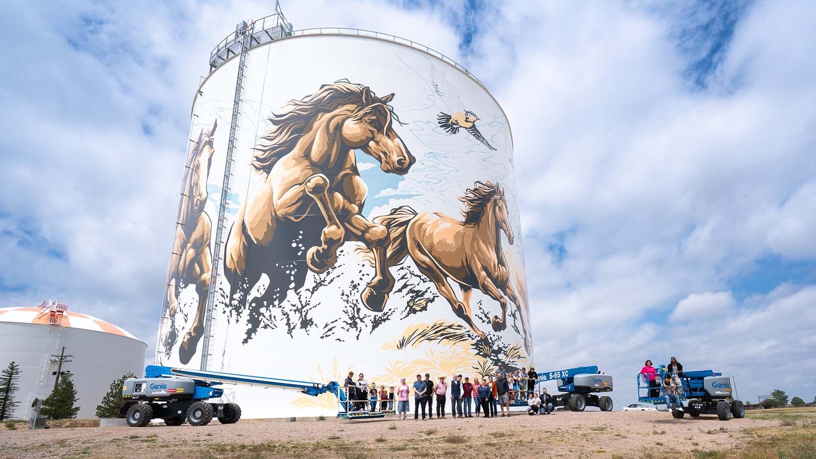 Paint crew members and their famlies pose in front of Cheyenne's water tank murals as they near completion.