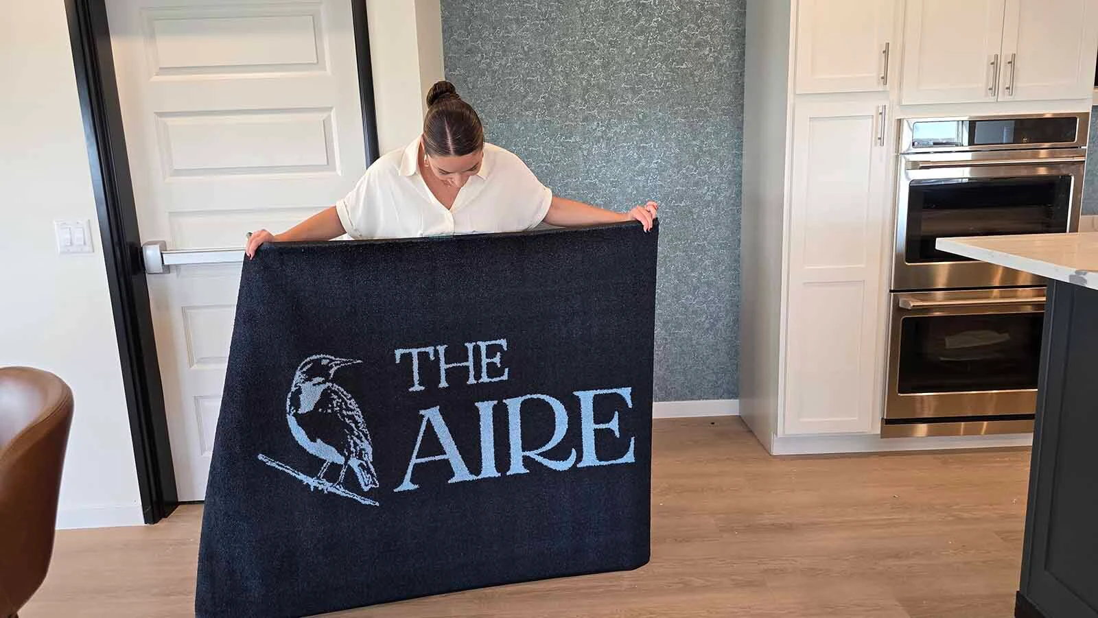 Property Manager Alana Skorupski holds up one of The Aire's logo rugs.