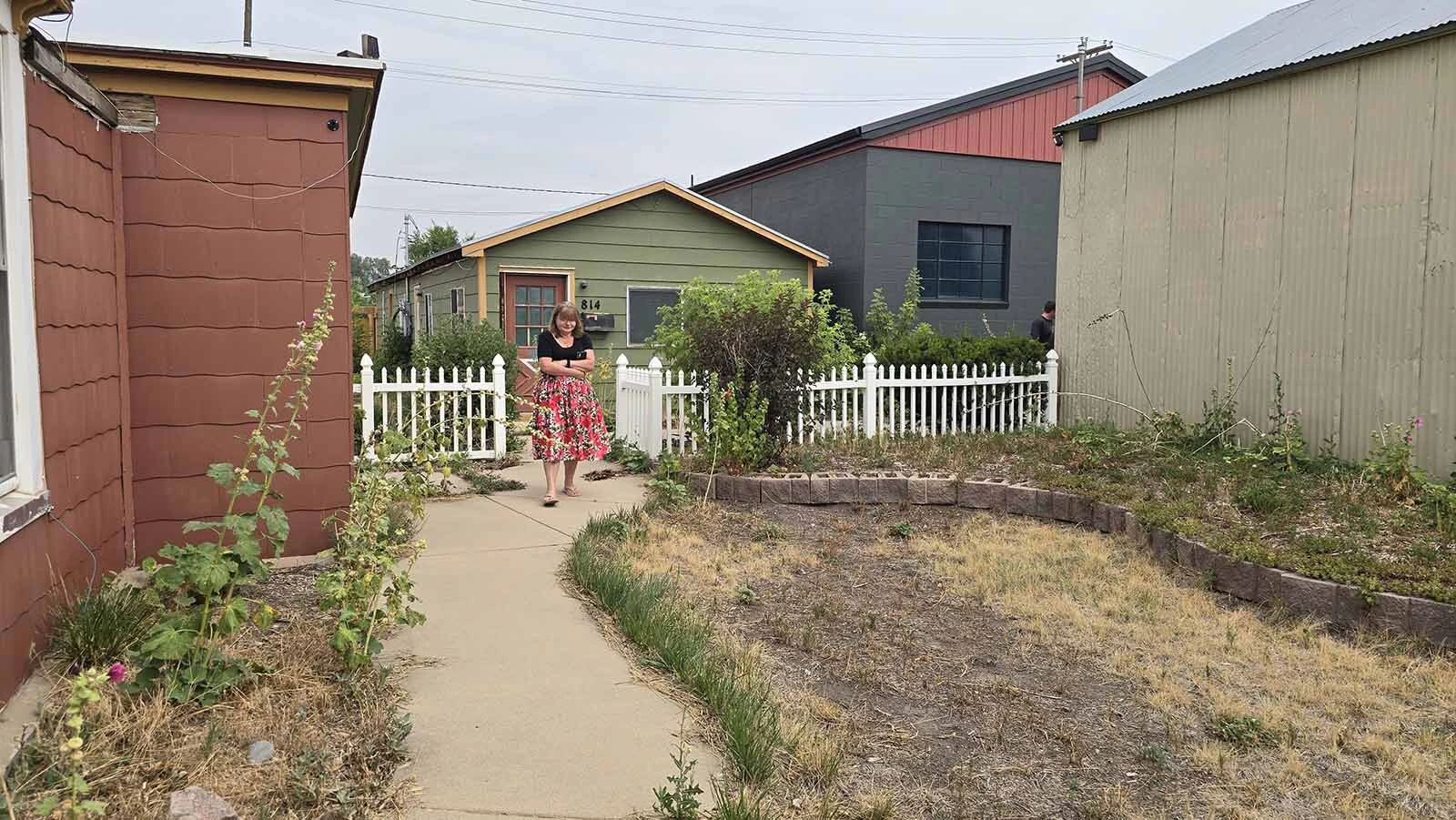 Sherrie Lyle walks up the pathway between the mini red Victorian home and its associated carriage house. Lyle and her children have purchased the property to turn it into a retail destination in Cheyenne's distressed Reed Avenue Corridor.