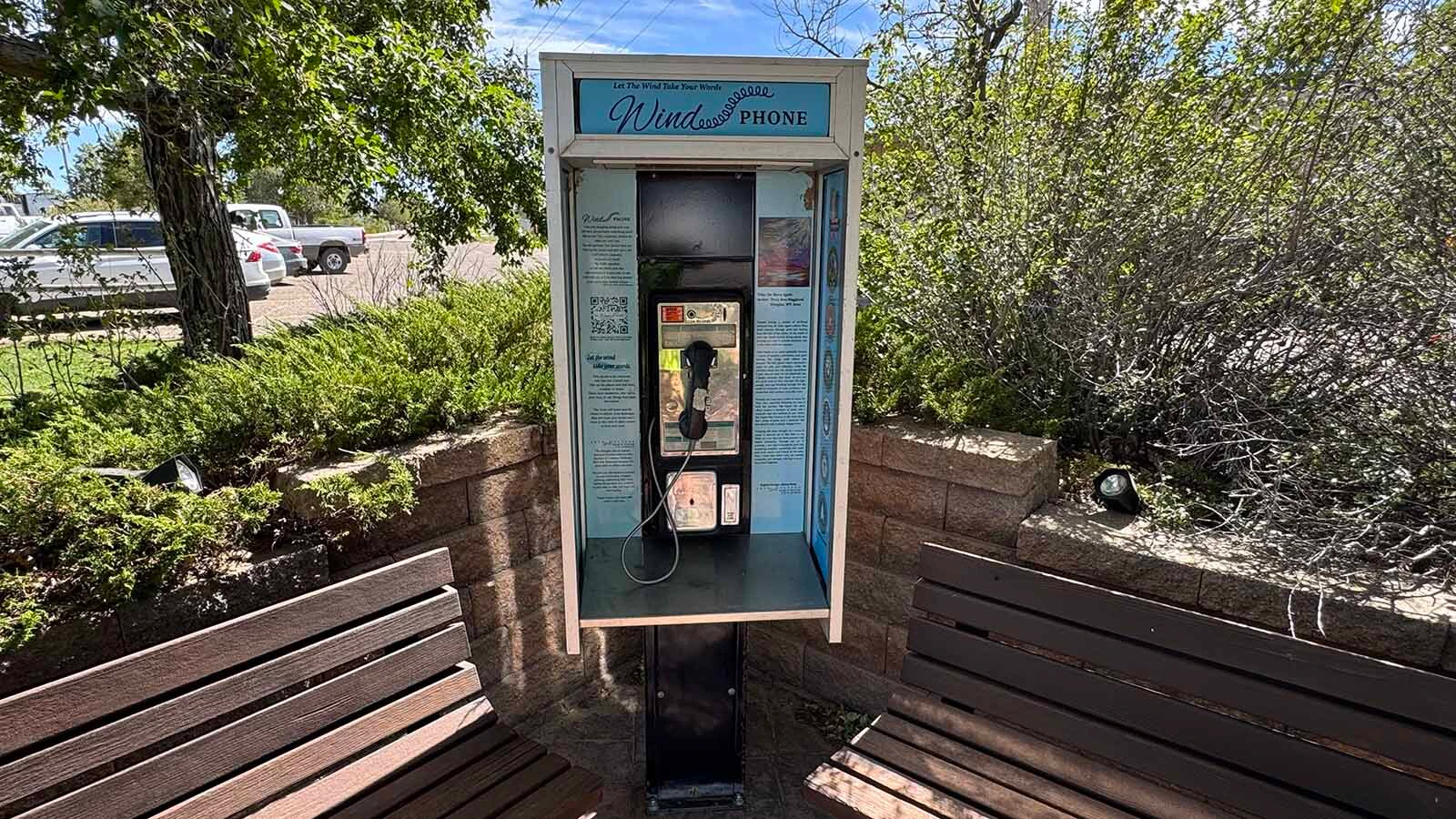 An old payphone sits between two benches beneath the trees along Douglas’ Veterans Walkway.