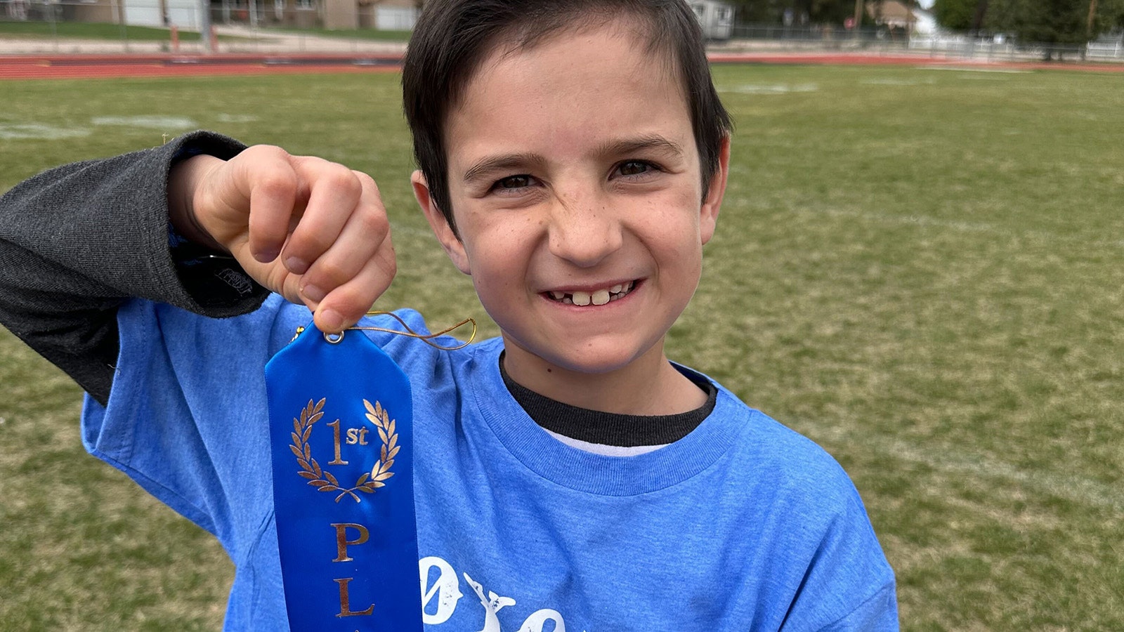 Wyatt Morgan proudly holds a blue ribbon he won.