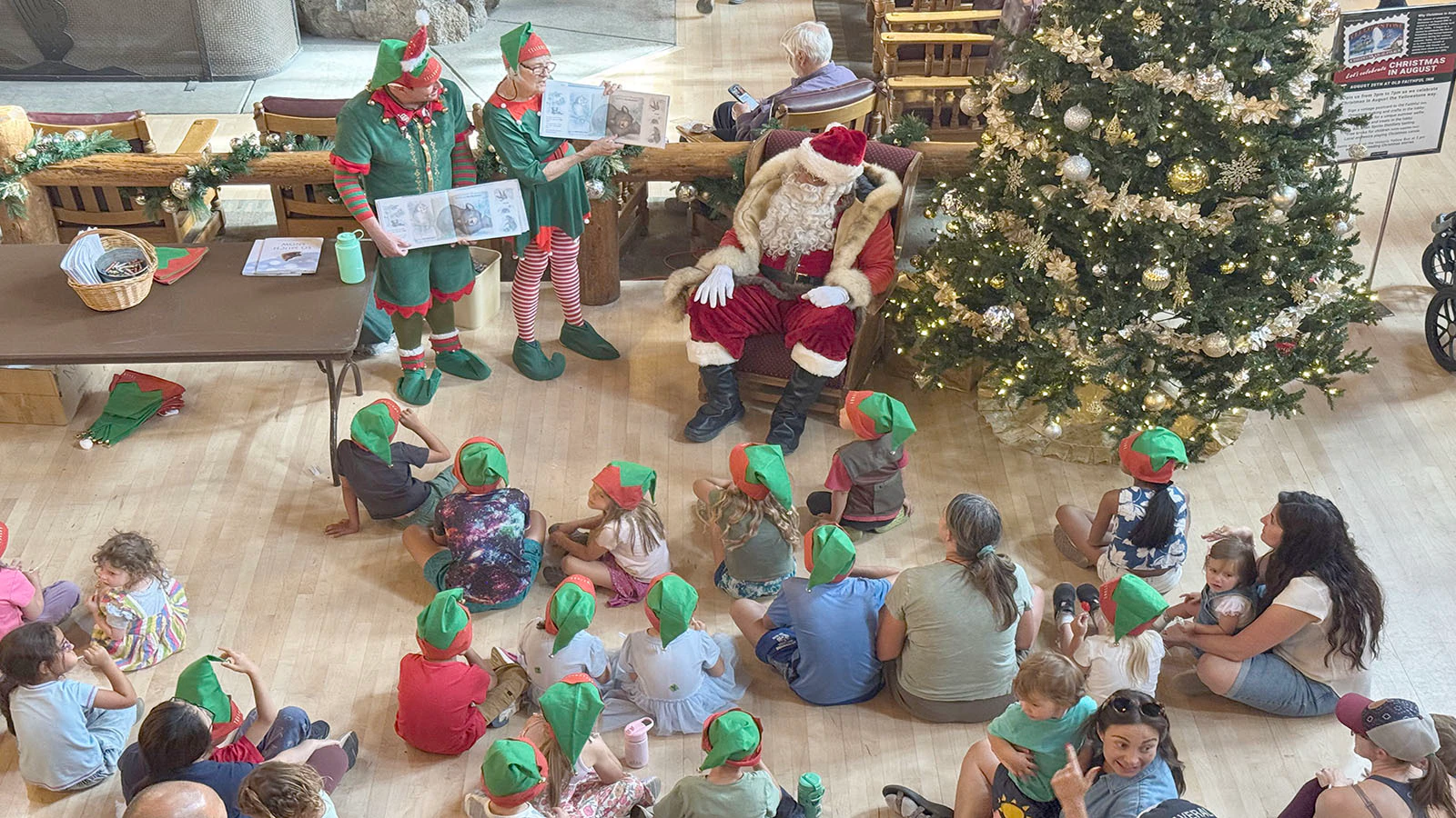 Santa Claus and his elves entertain tourists in the towering lobby of the Old Faithful Inn in an August tradition.