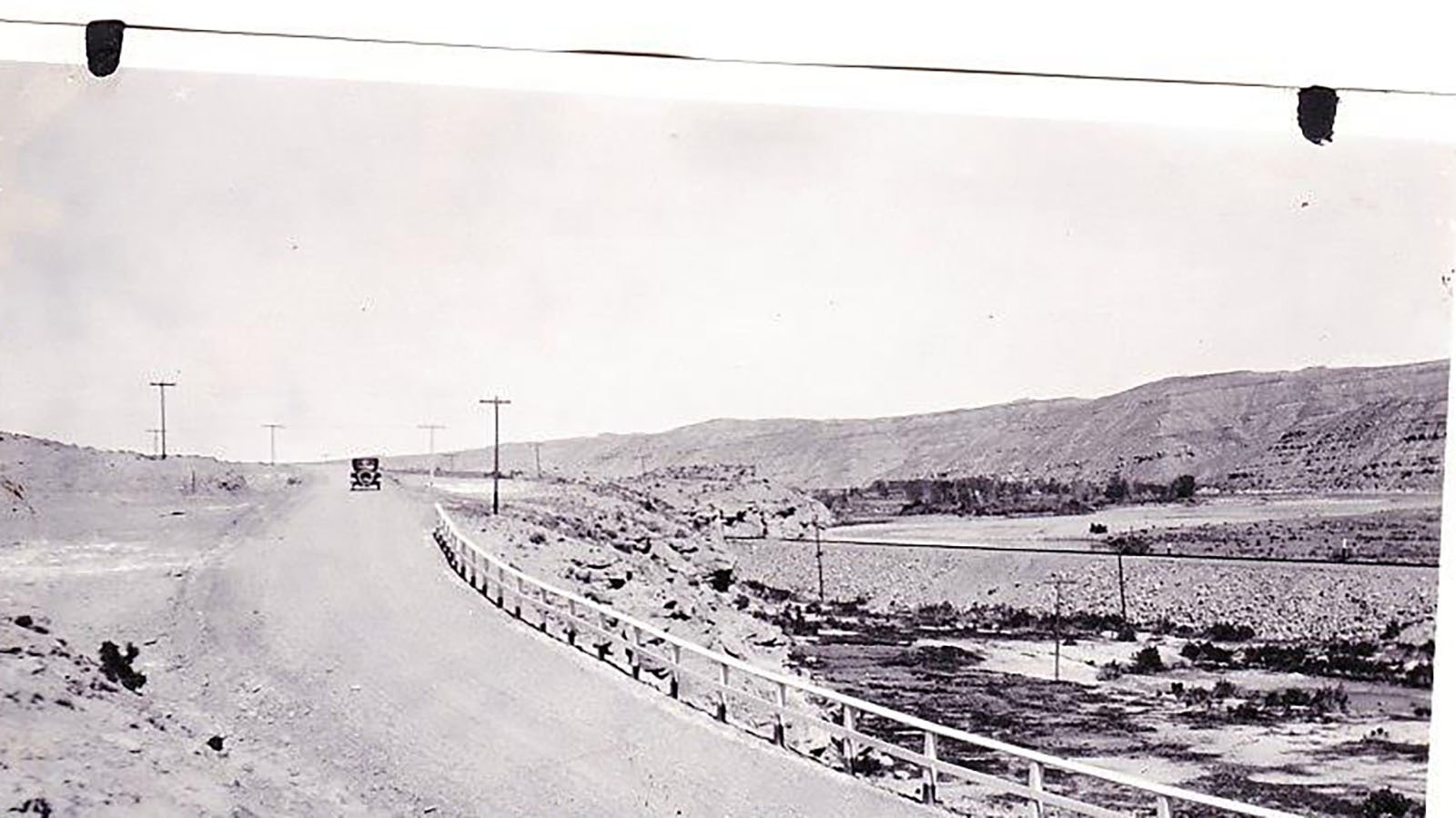 A car driving in the distance on the Yellowstone Highway north of Thermopolis in 1922 before the highway was completed.